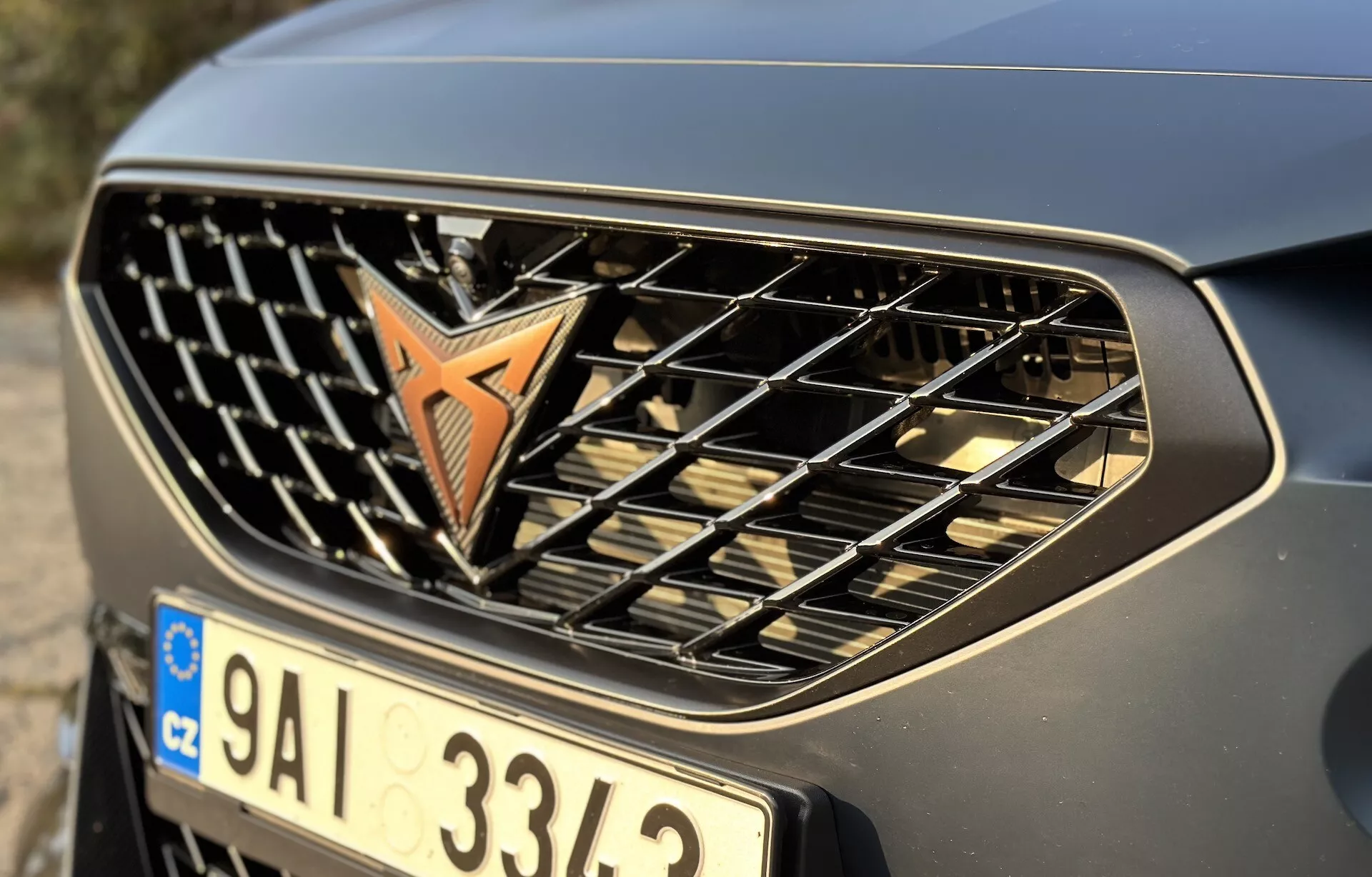 Zbliżenie na przedni grill i zderzak Cupra Formentor 2020 pokazujące emblemat, poziome listwy i metaliczne wykończenie, podkreślające jego design samochodowy i branding