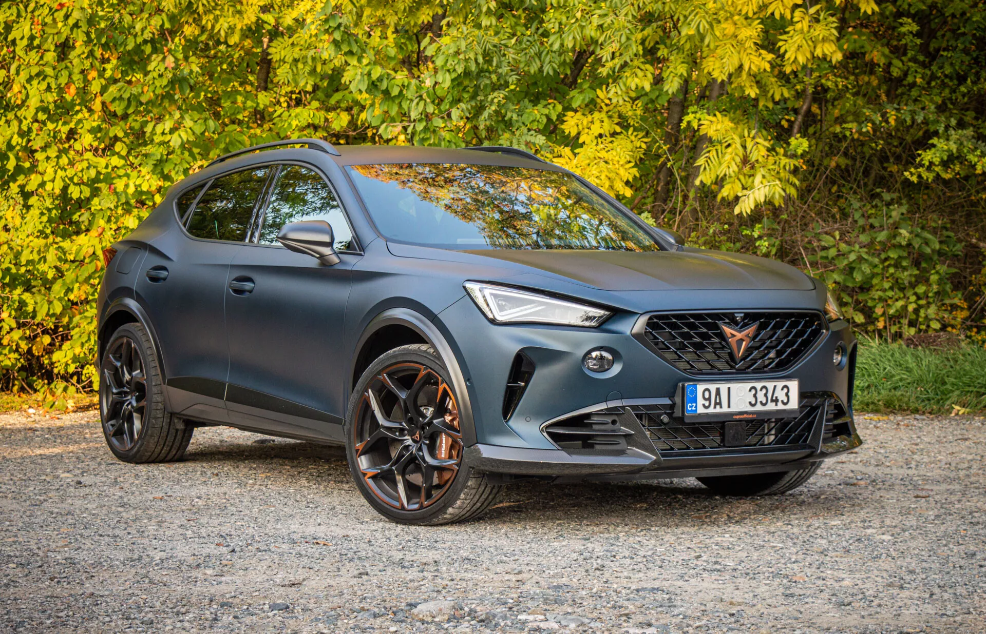 Crossover SUV Cupra Formentor 2020 zaparkowany na zewnątrz, pokazujący perspektywę trzy czwarte z przodu z naciskiem na sportowy design, fasadę przednią z reflektorami LED i grill, profil boczny z wieloramienne koła ze stopu i potencjalne zdolności terenowe
