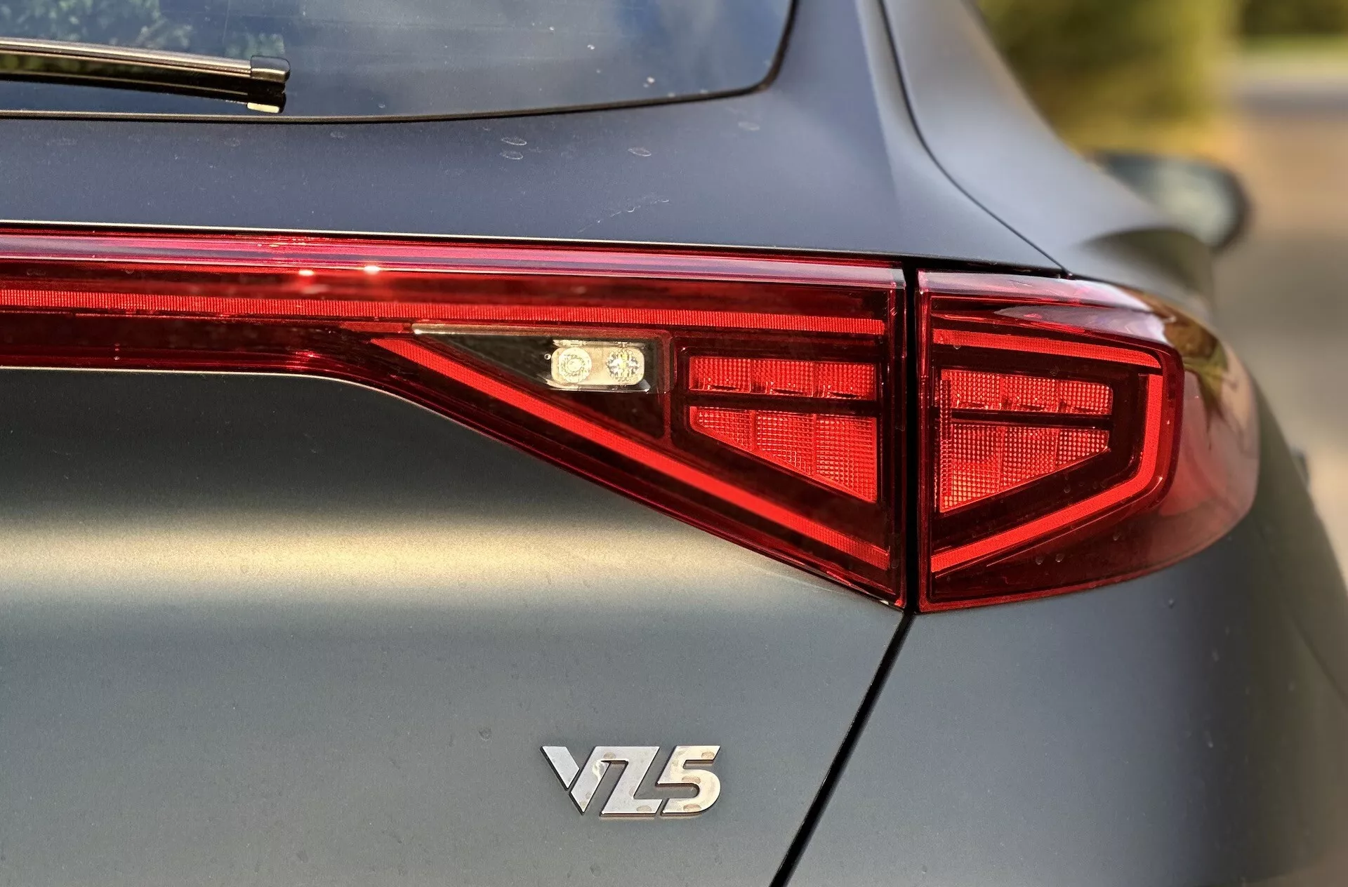 Tylny widok Cupra Formentor VZ5 z 2020 roku skupiający się na projekcie tylnych świateł LED, emblematu oraz wysokiej jakości metalicznego nadwozia, uchwycony z kąta trzech czwartych przy płytkiej głębi ostrości