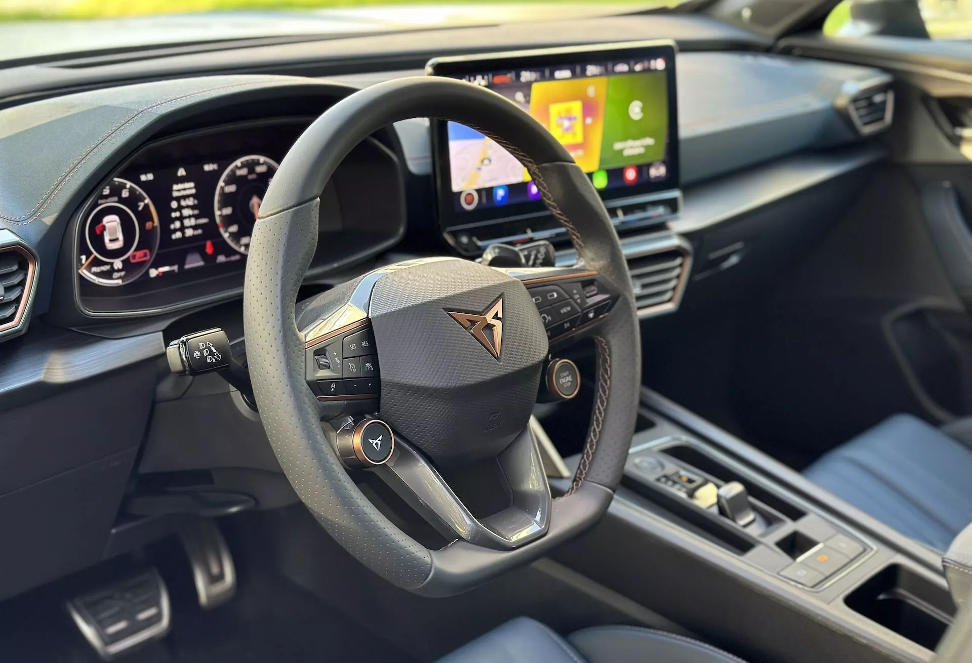 Widok wnętrza Cupra Formentor 2020 skupiony na perspektywie kierowcy z wyraźnym widokiem na wielofunkcyjną kierownicę, cyfrowy kokpit i część systemu infotainment, podkreślony nowoczesnym designem i zaawansowanymi funkcjami technologicznymi