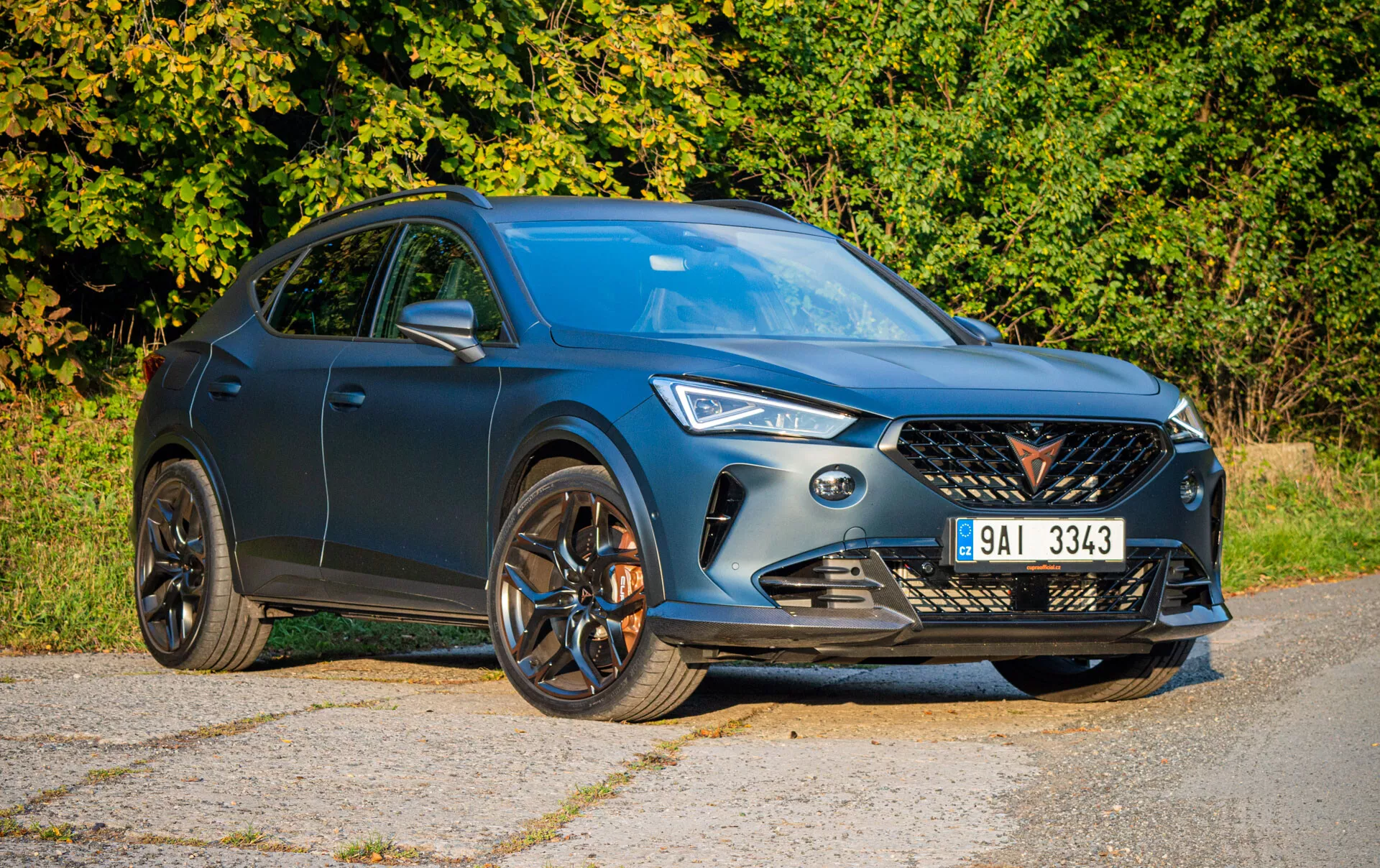 Niebieskie SUV Cupra Formentor 2020 prezentujące swoją dynamiczną przednią kratę, światła LED i sportowe felgi aluminiowe w ukośnym widoku z przodu i boku, odzwierciedlające nowoczesny i aerodynamiczny design w naturalnym świetle dziennym