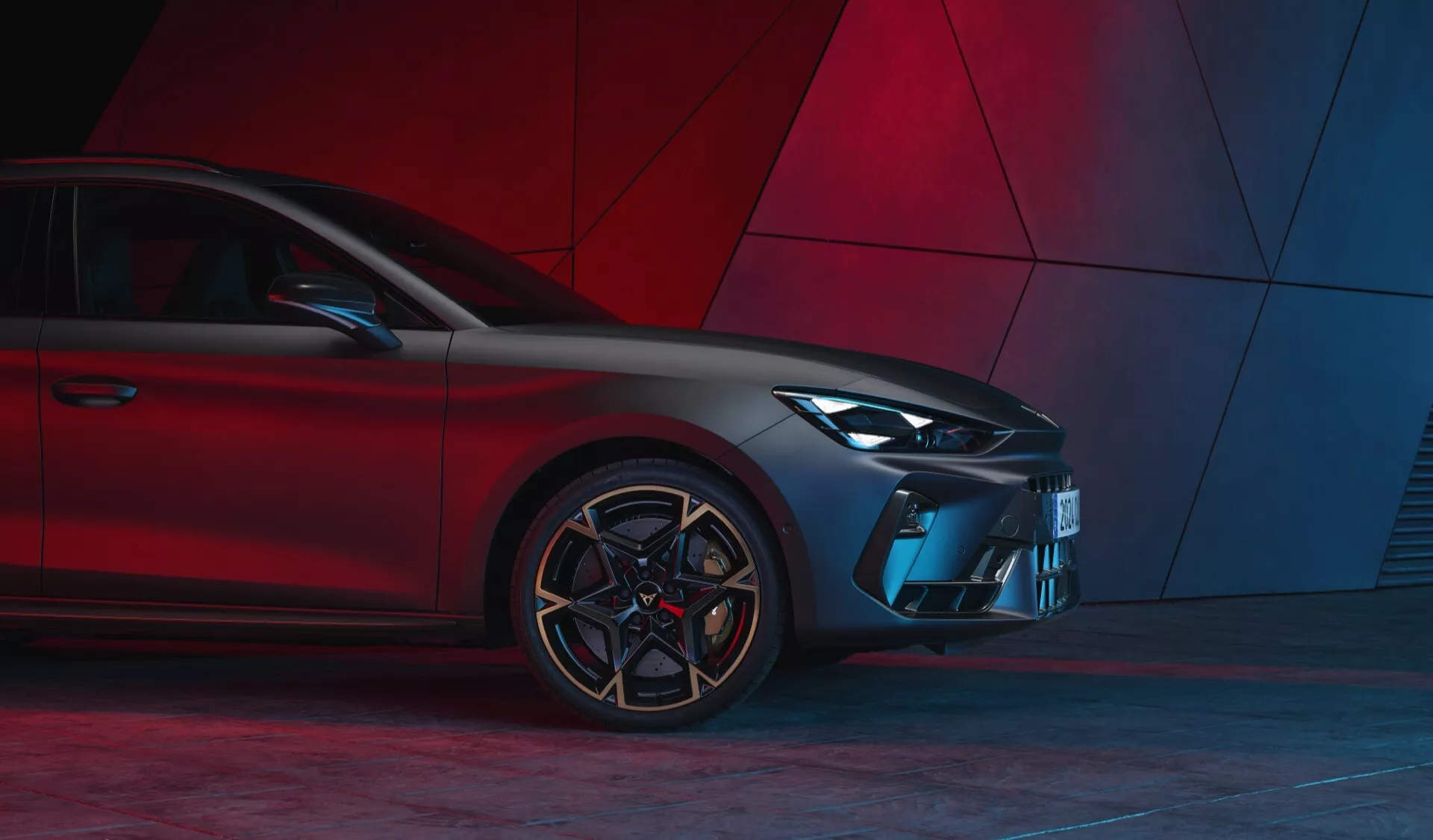 Trzy-czwarte przednie ujęcie Cupra Leon 2024 (lifting pierwszej generacji) podkreślające nowoczesny design z reflektorami LED, sportową kratką, rzeźbionym przednim zderzakiem, kątowymi wlotami powietrza, wieloszprychowymi felgami aluminiowymi i oponami niskoprofilowymi na abstrakcyjnym czerwonym tle.