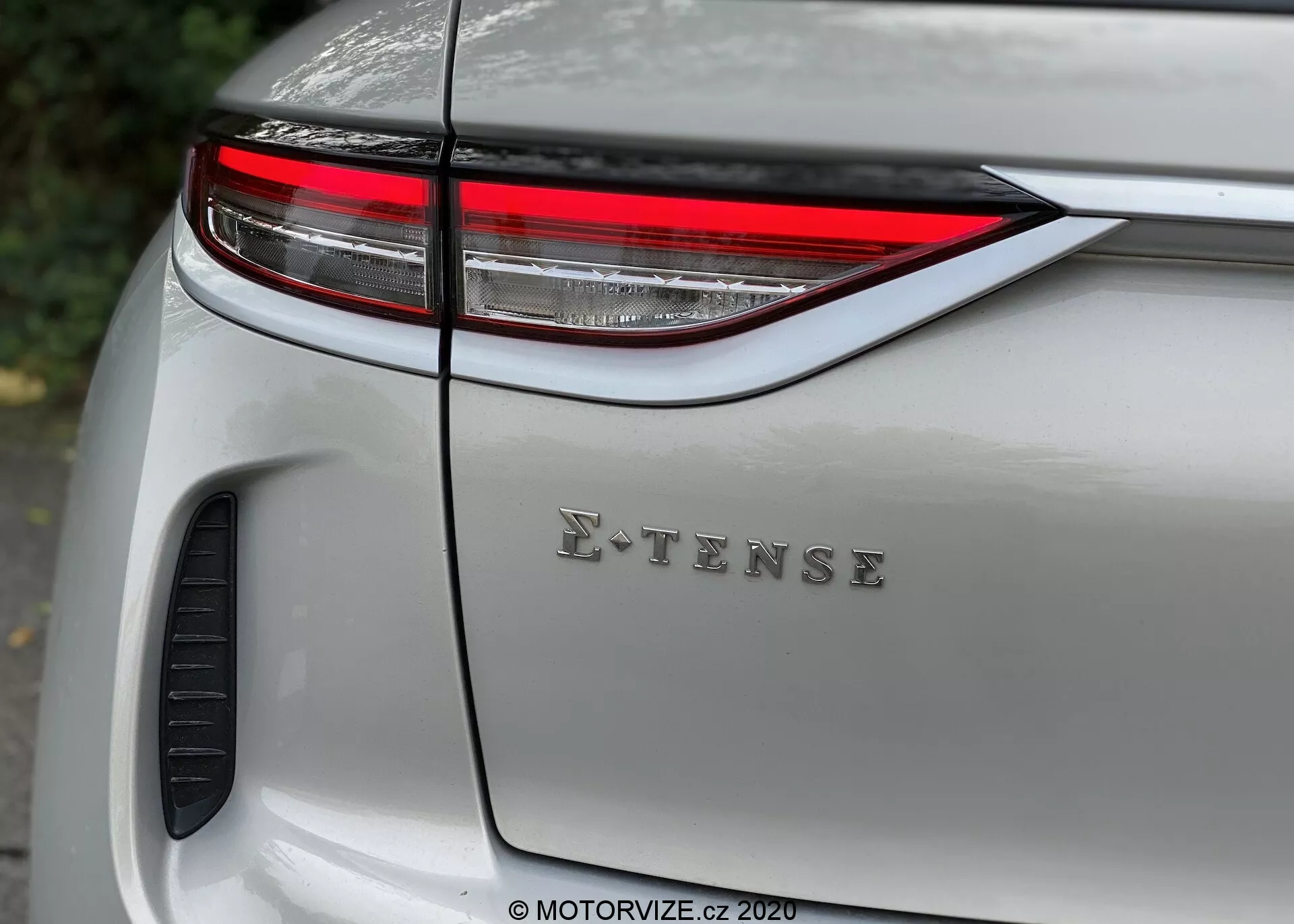 Zbliżenie tylnej sekcji nowoczesnego srebrnego DS Automobiles DS 3 Crossback E-Tense 2019, ukazującego eleganckie poziome światło tylne LED, znaczek E-TENSE na pokrywie bagażnika oraz błyszczące wykończenie lakieru z refleksami. Widoczny element projektu lub otwór wentylacyjny przy nadkolu, podkreślający projektowanie samochodowe, technologię i cechy przyjazne dla środowiska.