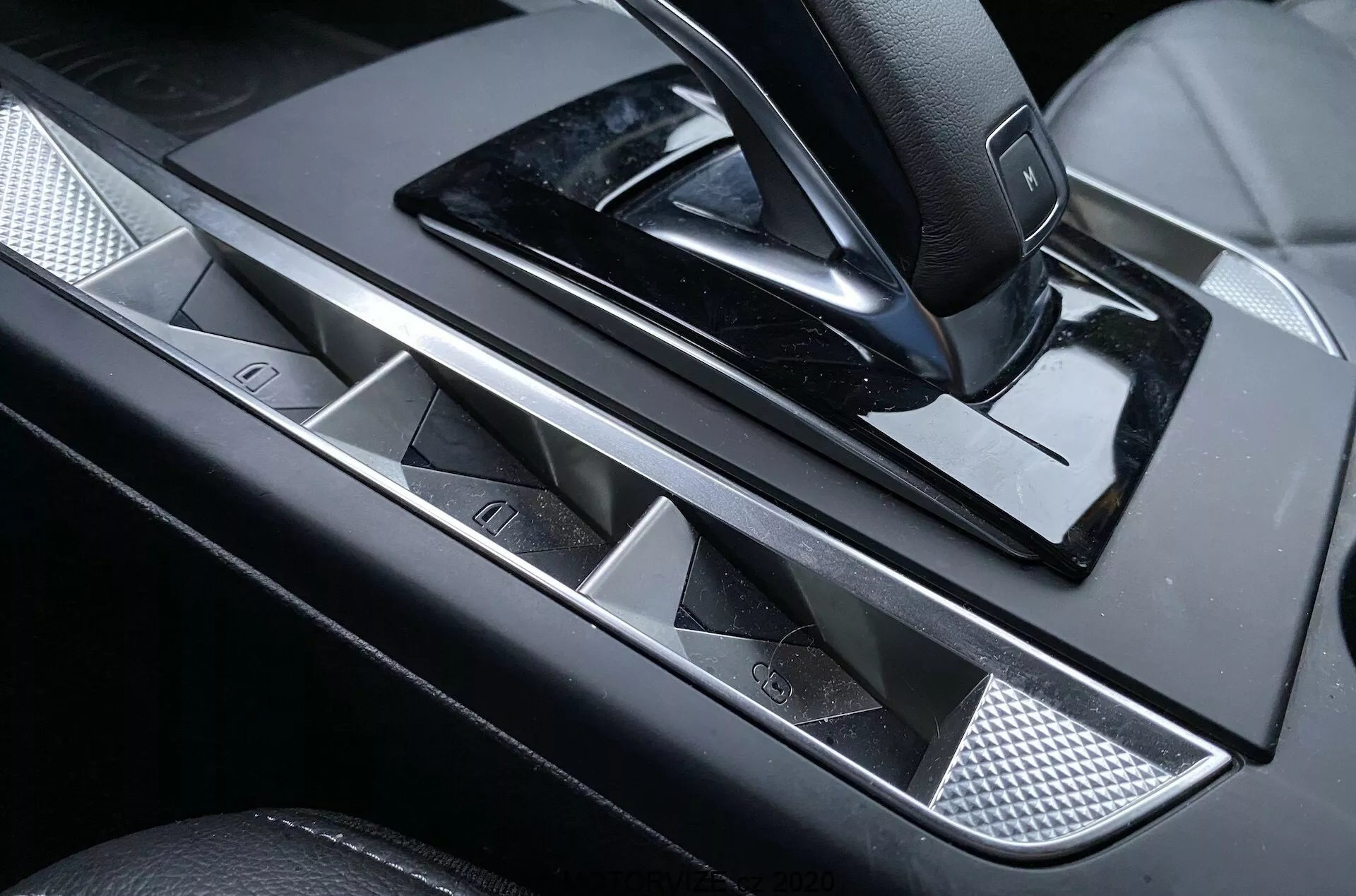 Zbliżenie na panel sterowania drzwi kierowcy luksusowego DS Automobiles DS-3 Crossback 2019, z elegancką metalową klamką, przyciskami szyb elektrycznych z chromowanymi akcentami, joystickiem do regulacji lusterek bocznych, wykończeniem na wysoki połysk i teksturowaną metalową wstawką dla dotyku wyrafinowania.