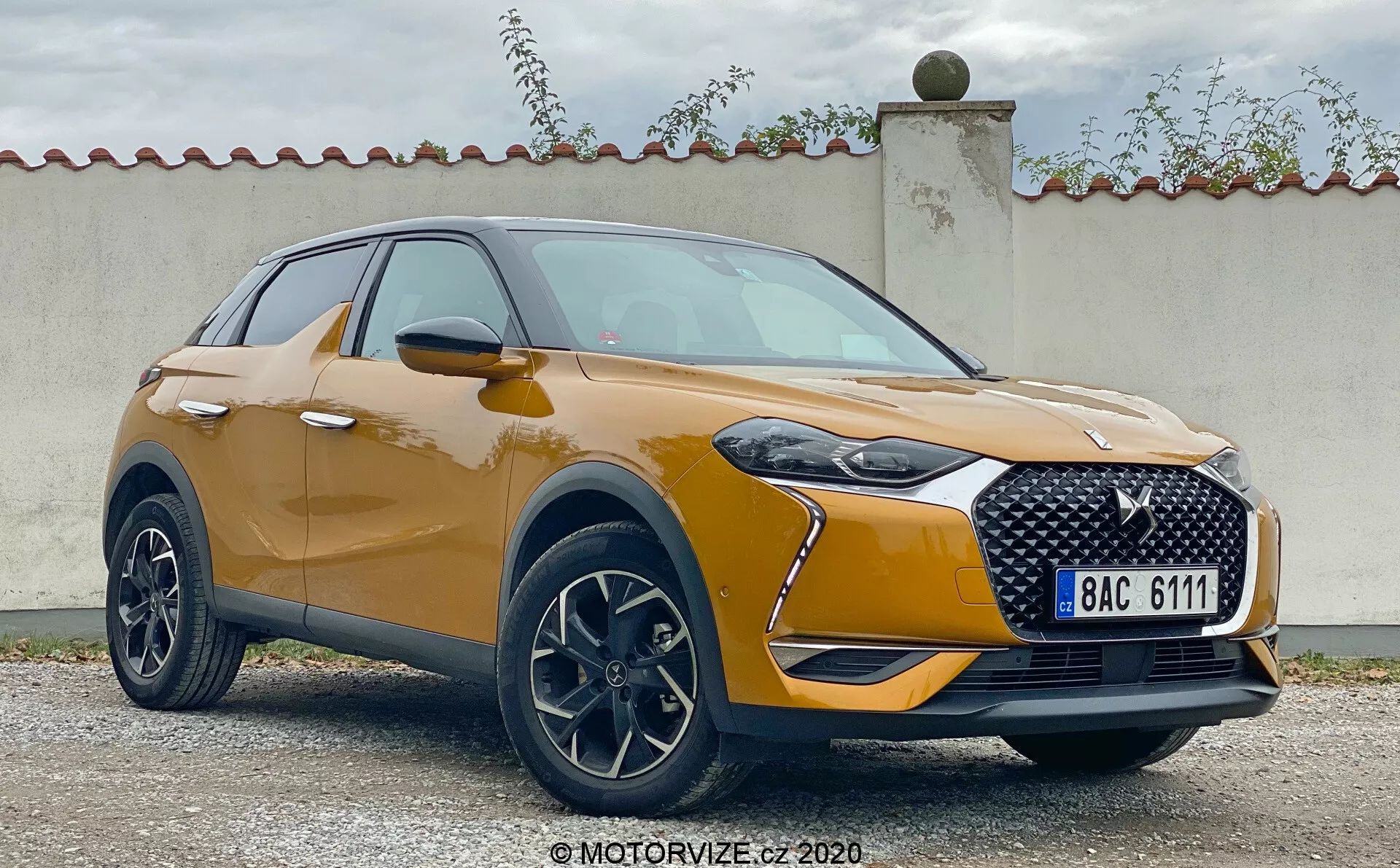Widok przód-trzy czwarte modelu DS Automobiles DS 3 Crossback 2019. Obraz pokazuje nowoczesny crossover SUV z charakterystycznym grillem, eleganckimi reflektorami LED i obudowami świateł przeciwmgielnych. Metaliczne wykończenie lakieru, gładki kontur maski i aluminiowe felgi podkreślają sportowy, a jednocześnie ekskluzywny design. Aerodynamicznie zaprojektowane lusterka boczne z wbudowanymi kierunkowskazami i plastikowe osłony wokół nadkoli dodają pojazdowi solidnego wyglądu.
