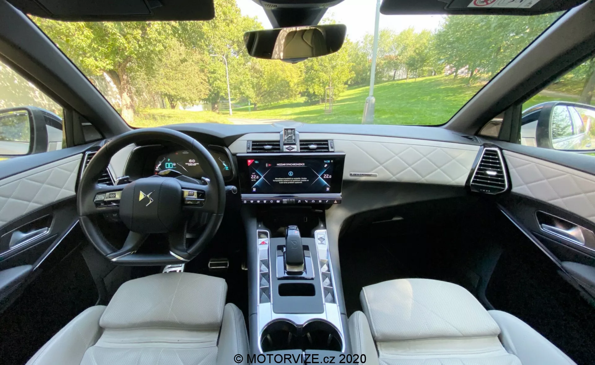 Wnętrze DS Automobiles DS 7 Crossback 2018 widziane z tylnego siedzenia, z wyróżnieniem skórzanej wielofunkcyjnej kierownicy, cyfrowego zestawu wskaźników, centralnego ekranu dotykowego systemu infotainment, panelu klimatyzacji, elektronicznego wybieraka biegów, luksusowych skórzanych siedzeń z diamentowym szwem oraz konsoli środkowej z uchwytami na kubki. Obraz pokazuje połączenie zaawansowanych technologii i wyszukanego designu.