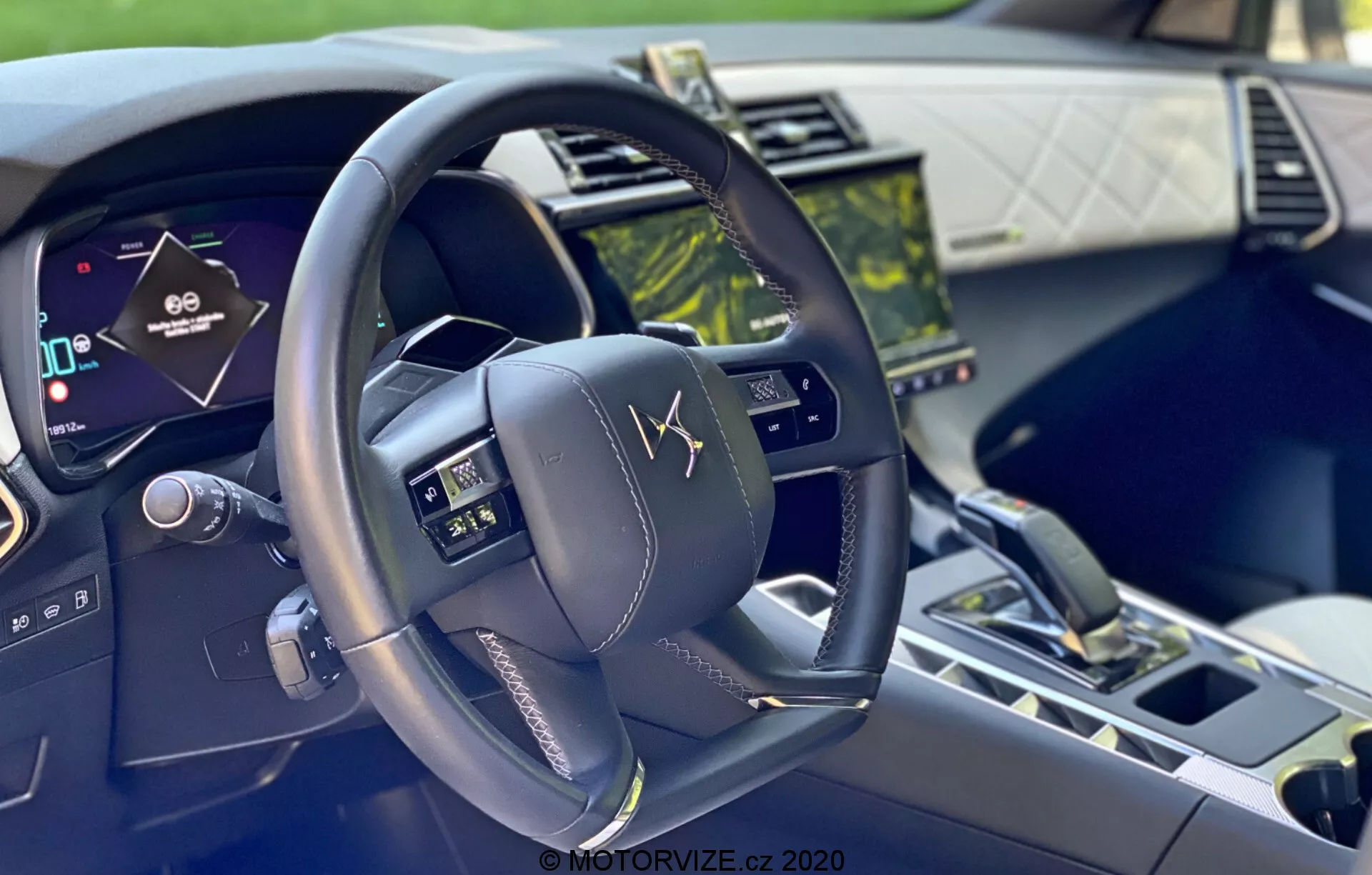 Zdjęcie wnętrza DS-7 Crossback 2018 z perspektywy kierowcy, ukazujące nowoczesną, wielofunkcyjną kierownicę z przyciskami kontrolnymi, cyfrowy zestaw wskaźników oraz dotykowy system multimedialny, podkreślające zaawansowaną technologię i luksusowe materiały.