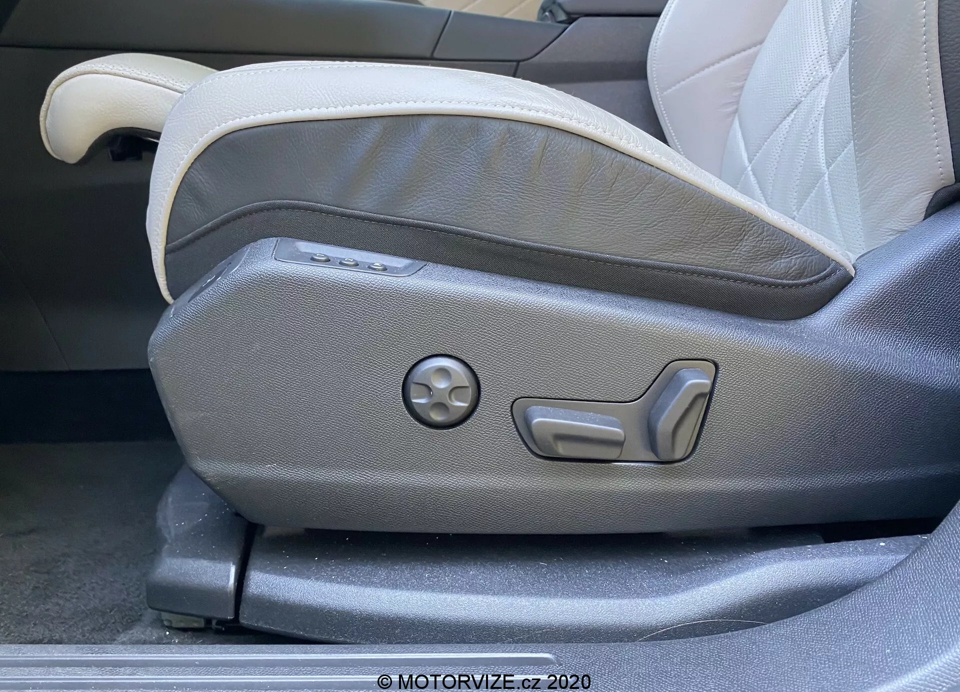 Zbliżenie na panel regulacji fotela kierowcy w DS Automobiles DS 7 Crossback z 2018 roku. Zdjęcie przedstawia elektrycznie sterowane elementy regulacji fotela, w tym przyciski do wielopoziomowej regulacji oraz okrągłe pokrętło do ustawień pamięci. Fotel ma dwukolorową tapicerkę w jasnoszarym i ciemnoszarym odcieniu, prezentując nowoczesny, ergonomiczny design charakterystyczny dla luksusowych wnętrz samochodowych.