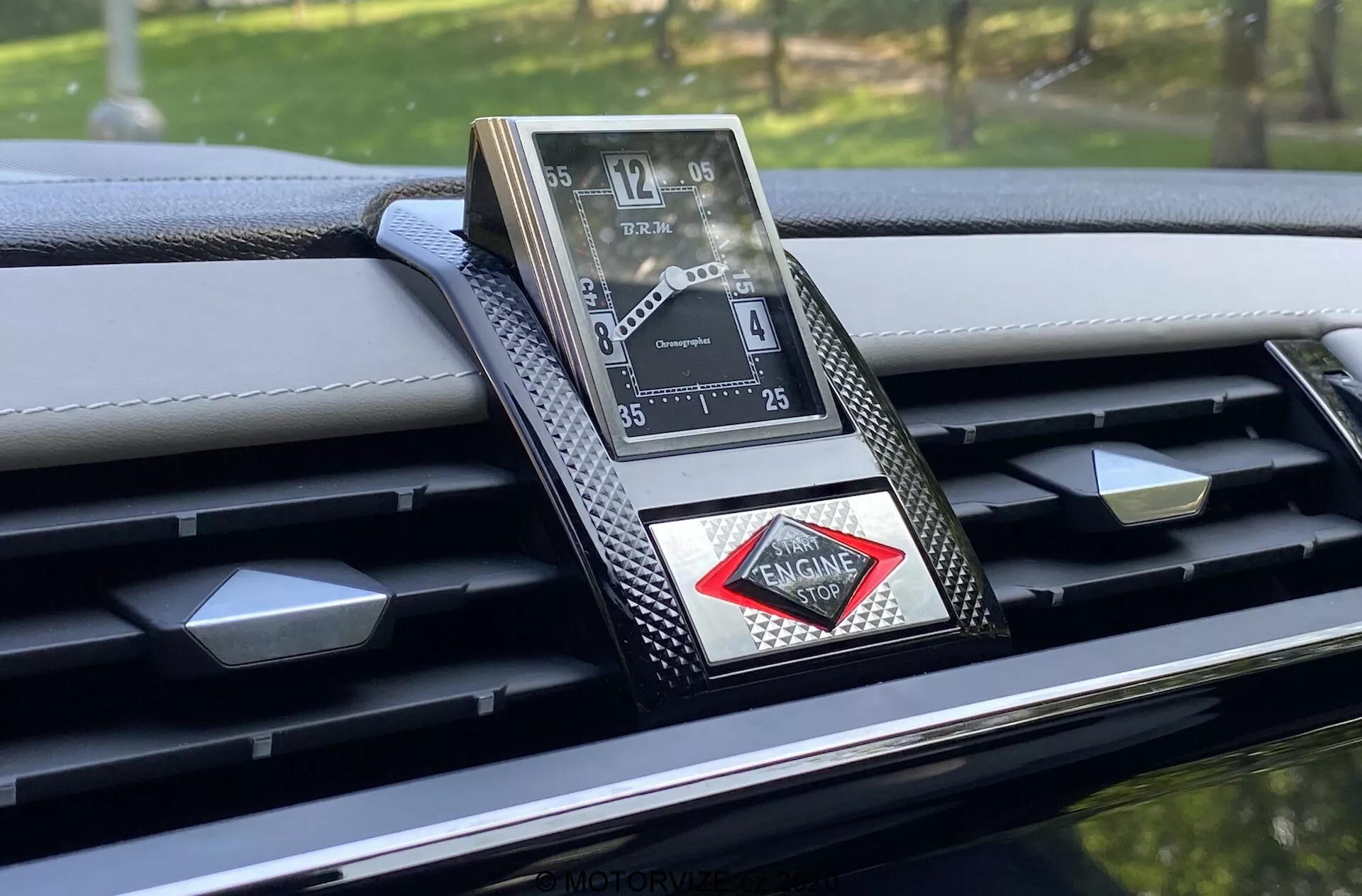 Zbliżenie luksusowego zegara analogowego wbudowanego w deskę rozdzielczą DS-7 Crossback 2018, charakteryzującego się wyrafinowanym designem z rzymskimi cyframi, metalicznym wykończeniem i logo w kształcie diamentu. Deska rozdzielcza ma akcenty z włókna węglowego i szczegółowe szwy, podkreślając wysokiej klasy rzemiosło i zaawansowane materiały w tym luksusowym wnętrzu samochodu.