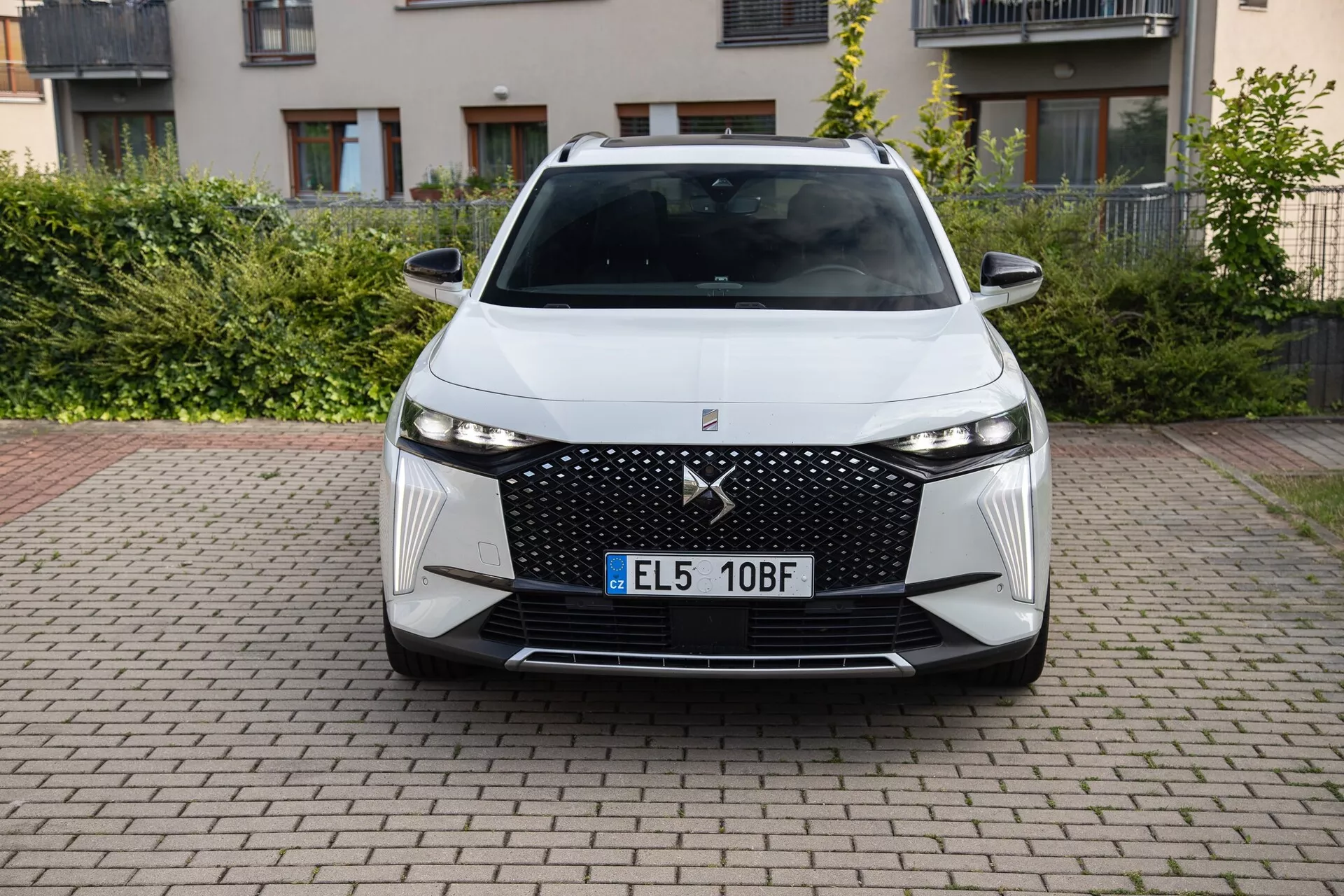 Przedni widok DS Automobiles DS-7 2022 prezentujący jego nowoczesny design, z dużym grillem w wzór diamentu, wąskimi reflektorami LED, kątowymi wlotami powietrza i zaawansowanymi systemami wspomagania kierowcy