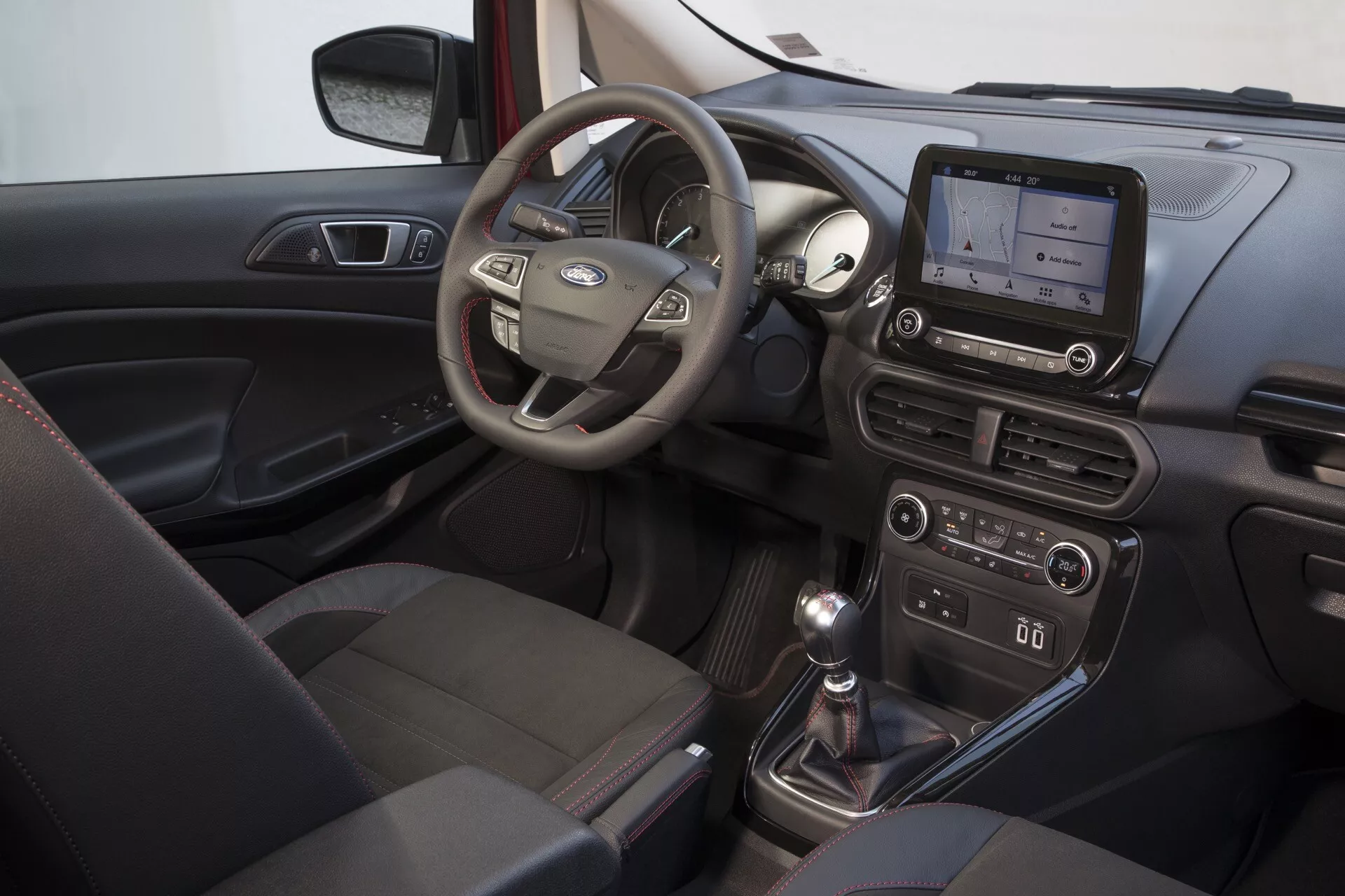 Wnętrze Ford EcoSport 2017 (1. generacja - Facelift) skupione na stronie kierowcy z wielofunkcyjną kierownicą, wyświetlaczem systemu infotainment na desce rozdzielczej, manualną skrzynią biegów i systemem kontroli klimatu
