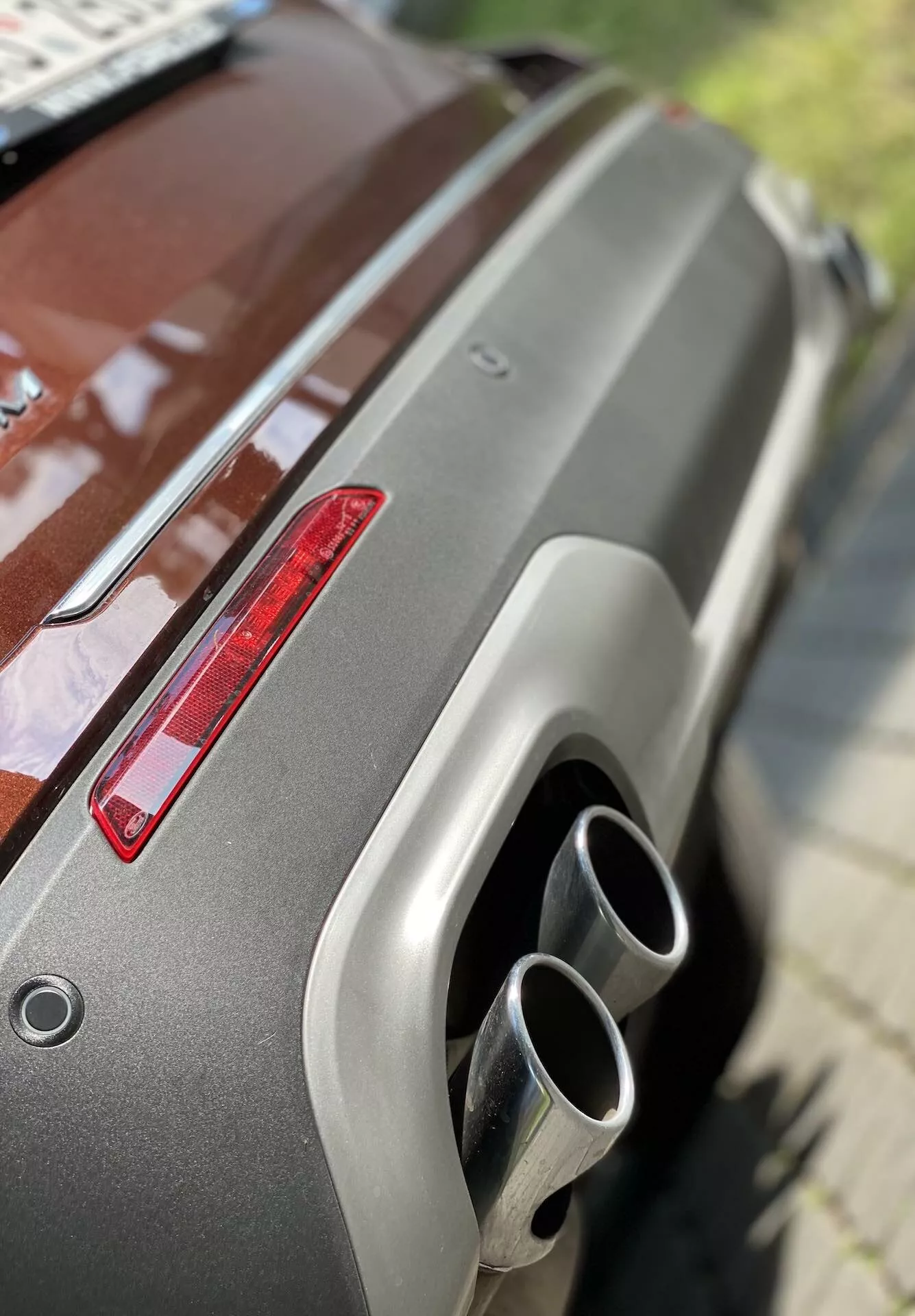 Zbliżenie tylnej części Forda Explorer 2019, pokazujące metaliczny lakier, tylny spojler, czerwone światło tylne oraz podwójne chromowane końcówki wydechu. Skośny kąt z podwyższonej pozycji podkreśla dobrze utrzymane wykończenie i nowoczesne cechy projektowe.