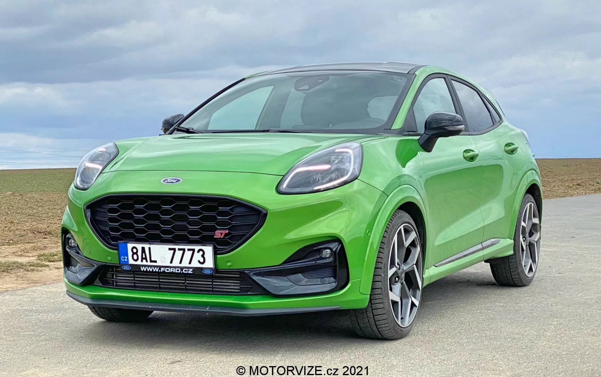 Ford Puma ST 2020 nowoczesny hatchback w jasnym zielonym kolorze z wyraźnym grillem w kształcie plastra miodu, eleganckimi, kanciastymi reflektorami, zderzakiem w kolorze nadwozia i wieloramiennymi felgami aluminiowymi nastawionymi na osiągi uchwyconymi z niskiego kąta w trzy czwarte widoku, ukazującym dynamiczną sylwetkę, aerodynamiczny profil i sportowy design w plenerze.
