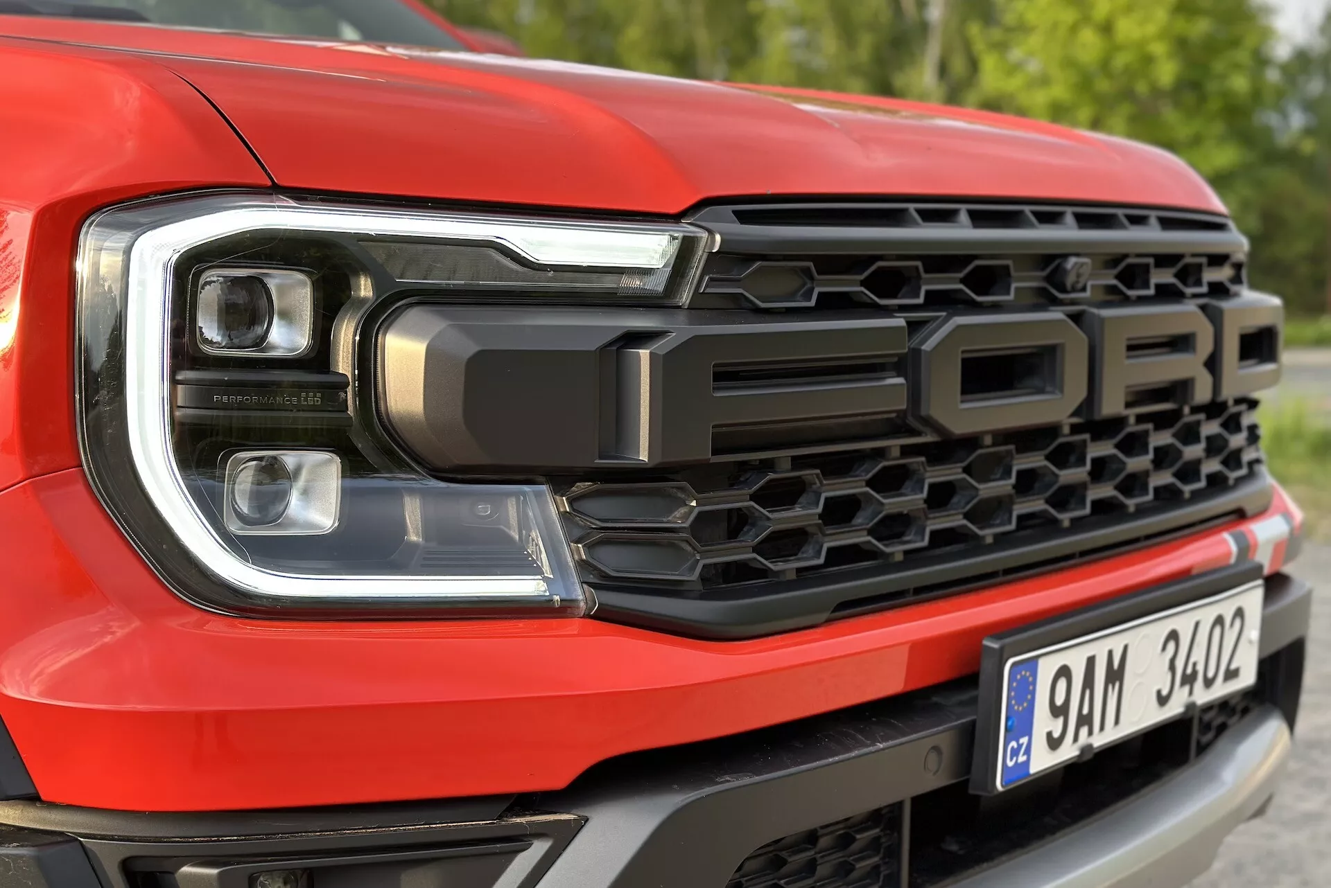 Zbliżenie na przednią lewą stronę Forda Rangera 2022, podkreślające projekt reflektorów LED i wzór grilla plastra miodu, z napisem 'FORD'