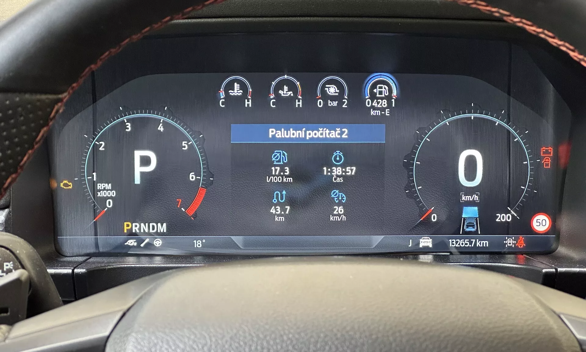 Widok z miejsca kierowcy na cyfrowy kokpit Ford Ranger 2022 pokazujący obrotomierz, wskaźnik paliwa, prędkościomierz, wyświetlacz temperatury i selektor biegów na nowoczesnym desce rozdzielczej pojazdu