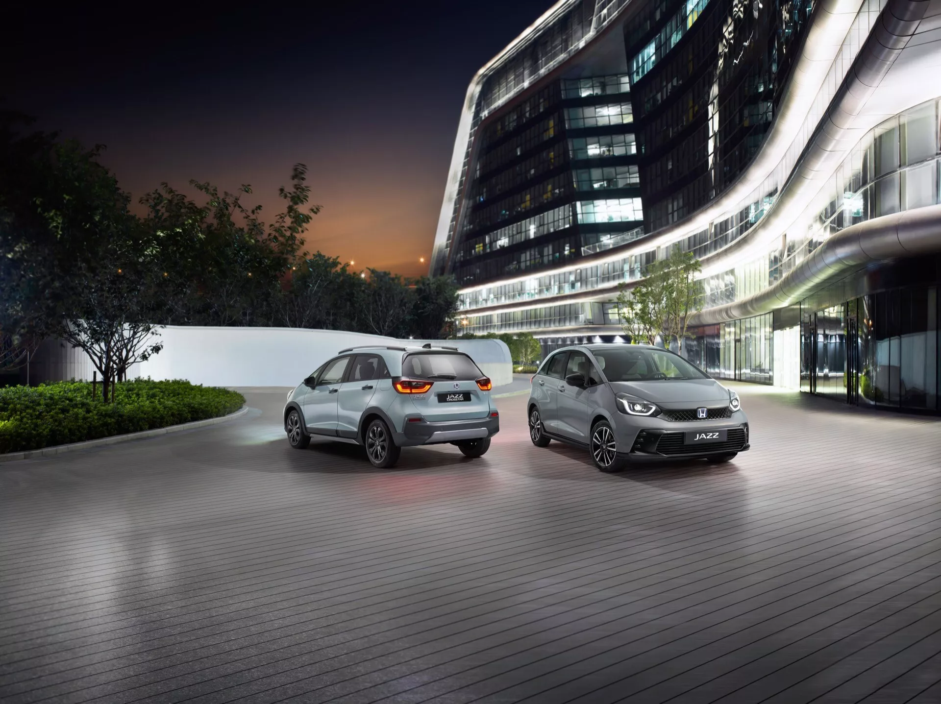 Honda Jazz 5. generacji facelifting 2023 prezentowana w luksusowym środowisku miejskim o zmierzchu, pokazująca zaawansowane cechy projektowe i technologię oświetleniową