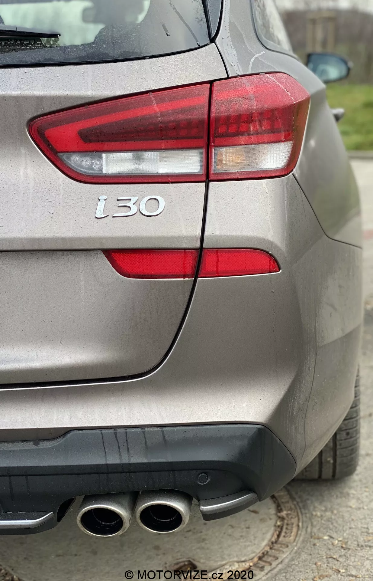 Zbliżenie na tylne trzy czwarte widoku srebrnego Hyundai i30 2020, podkreślające jego lewe światło tylne, tylny zderzak, cztery końcówki wydechu, oznaczenie „t30” oraz metaliczne wykończenie lakieru, podkreślające szczegóły projektu i wydajności pojazdu.