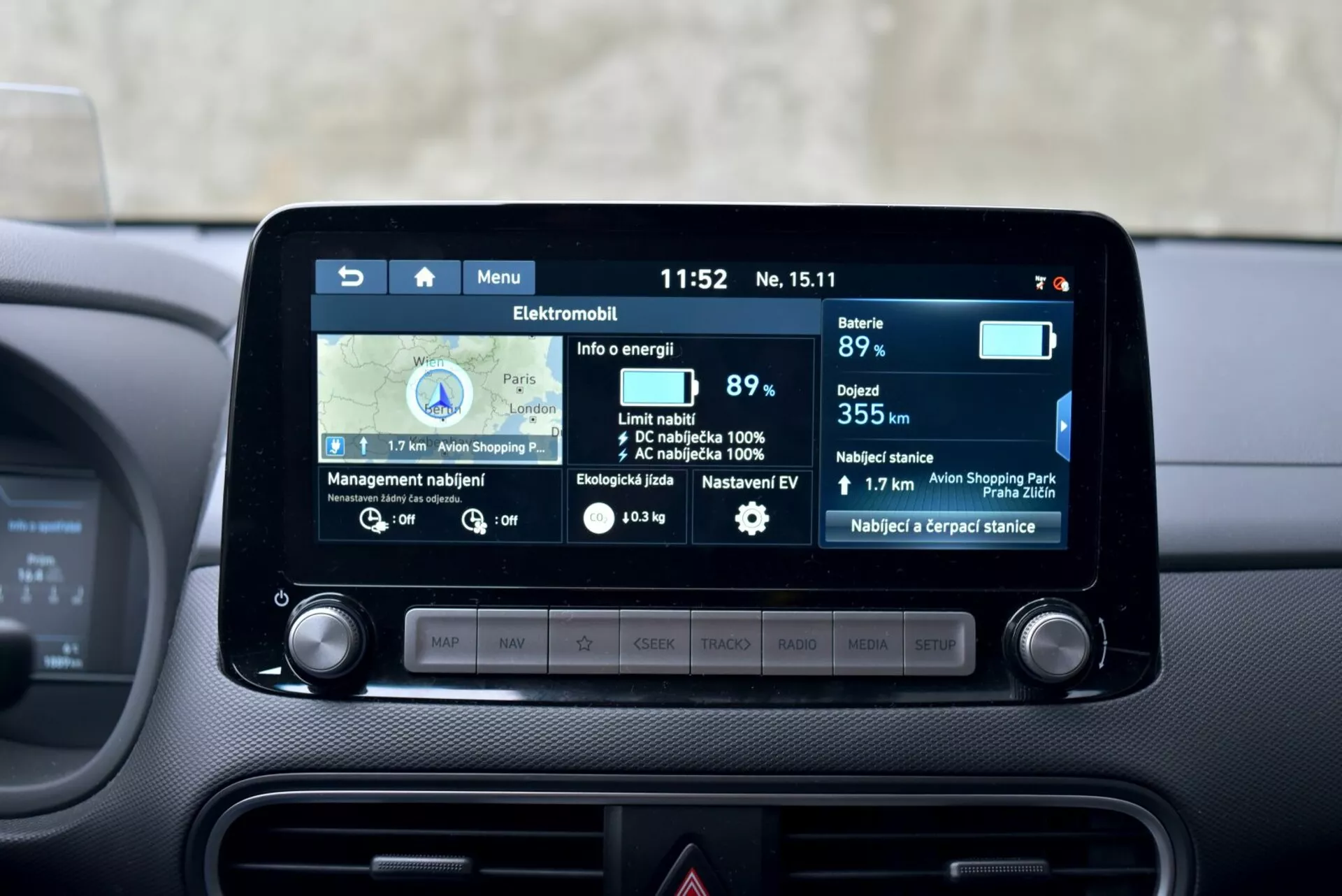 Centralna deska rozdzielcza elektrycznej Hyundaia Kona z 2021 roku z 8-calowym ekranem dotykowym infotainment pokazującym nawigację i funkcje pojazdu elektrycznego, w tym wskaźnik baterii na poziomie 89%, zasięg 355 km, statystyki zużycia energii i pobliskie stacje ładowania.