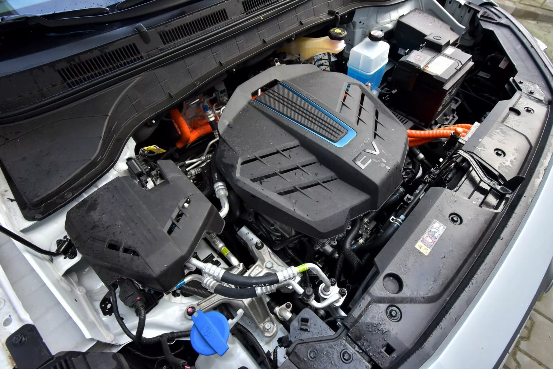 Zbliżony widok otwartej komory silnika Hyundai Kona 2021 (Kona Elektro) z naciskiem na centralny układ napędowy i wysokonapięciowe kable, ilustrujący technologię pojazdów elektrycznych tego modelu.