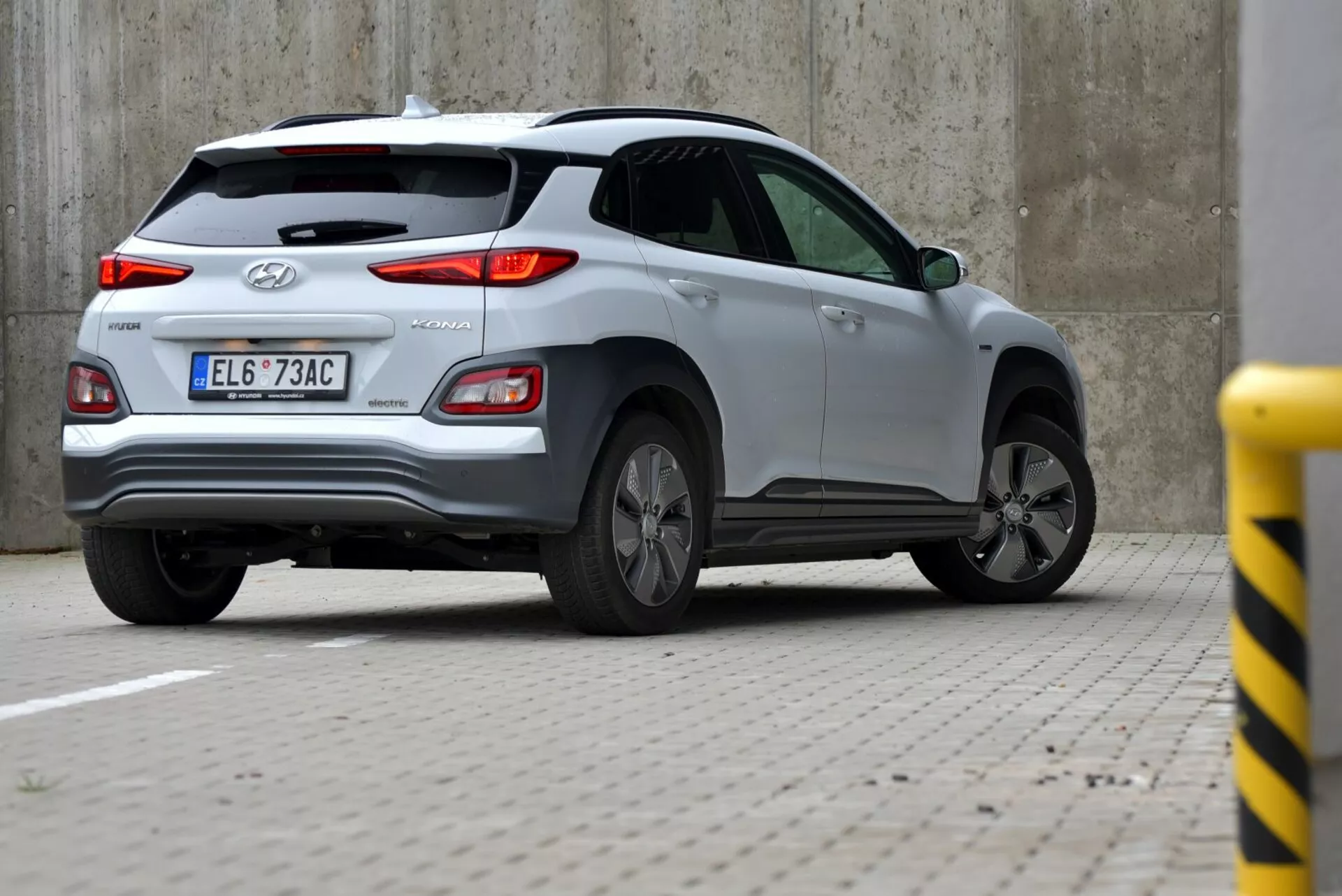 Srebrny Hyundai Tucson 2021 uchwycony z tylnego kąta trzech czwartych, prezentujący klapę bagażnika, lewe tylne koło i bok karoserii z widocznym tylnym światłem, logo Hyundai oraz napis TUCSON, w tym wycieraczkę tylnej szyby, antenę płetwy rekina i wzór koła ze stopu.