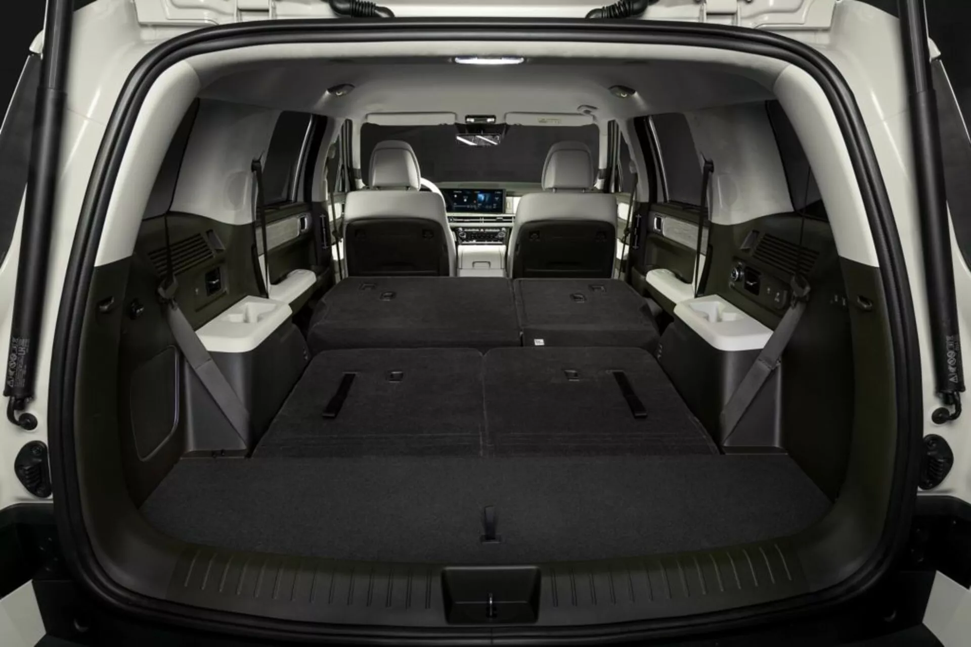 Wnętrze przestrzeni ładunkowej SUV Hyundai Santa Fe 2024 (5. generacja) z rozłożonymi tylnymi siedzeniami, podkreślające przestronny bagażnik i wszechstronność siedzeń. Środkowy rząd siedzeń ze skóry, zdjęcie na wprost z tyłu podkreślające głębokość i użyteczność przestrzeni bagażowej.