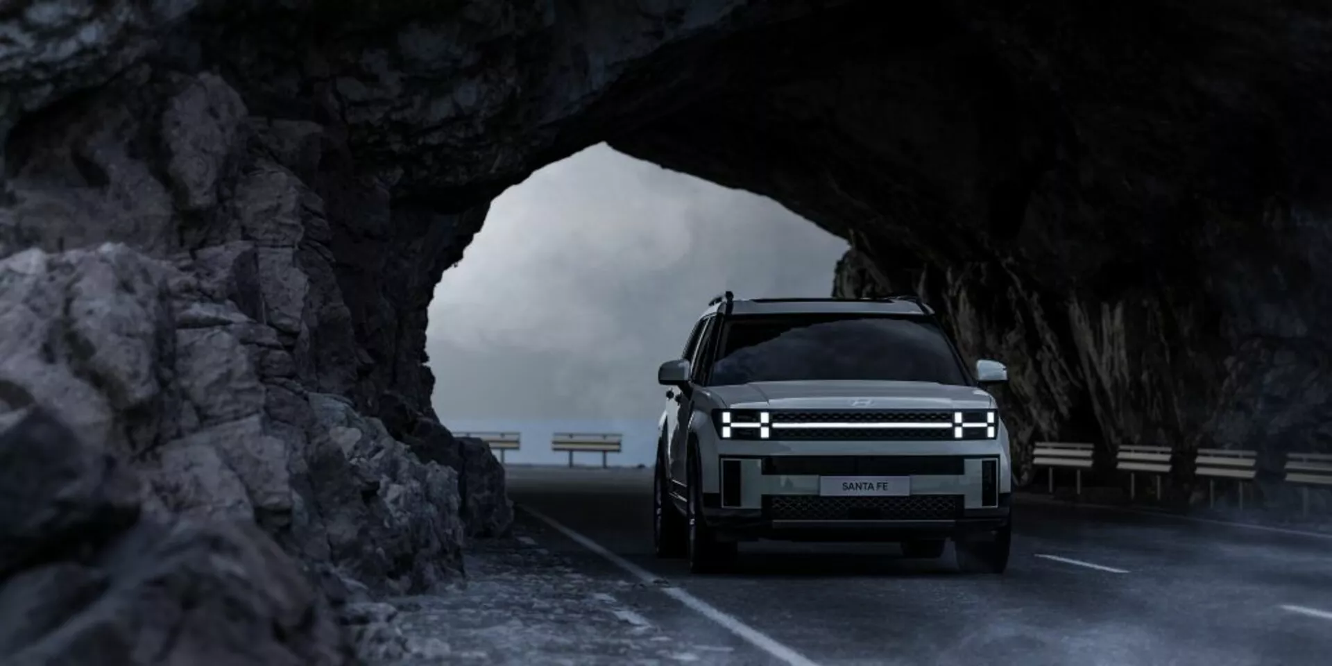 Widok z przodu Hyundai Santa Fe 2024 (5. generacja) w tunelu skalnym, podkreślający poziome reflektory LED, dużą przednią kratkę sugerującą możliwy model elektryczny i luksusowy design z podświetlanym logo, uchwycony w miękkim oświetleniu, podkreślający jego solidność i potencjał terenowy.