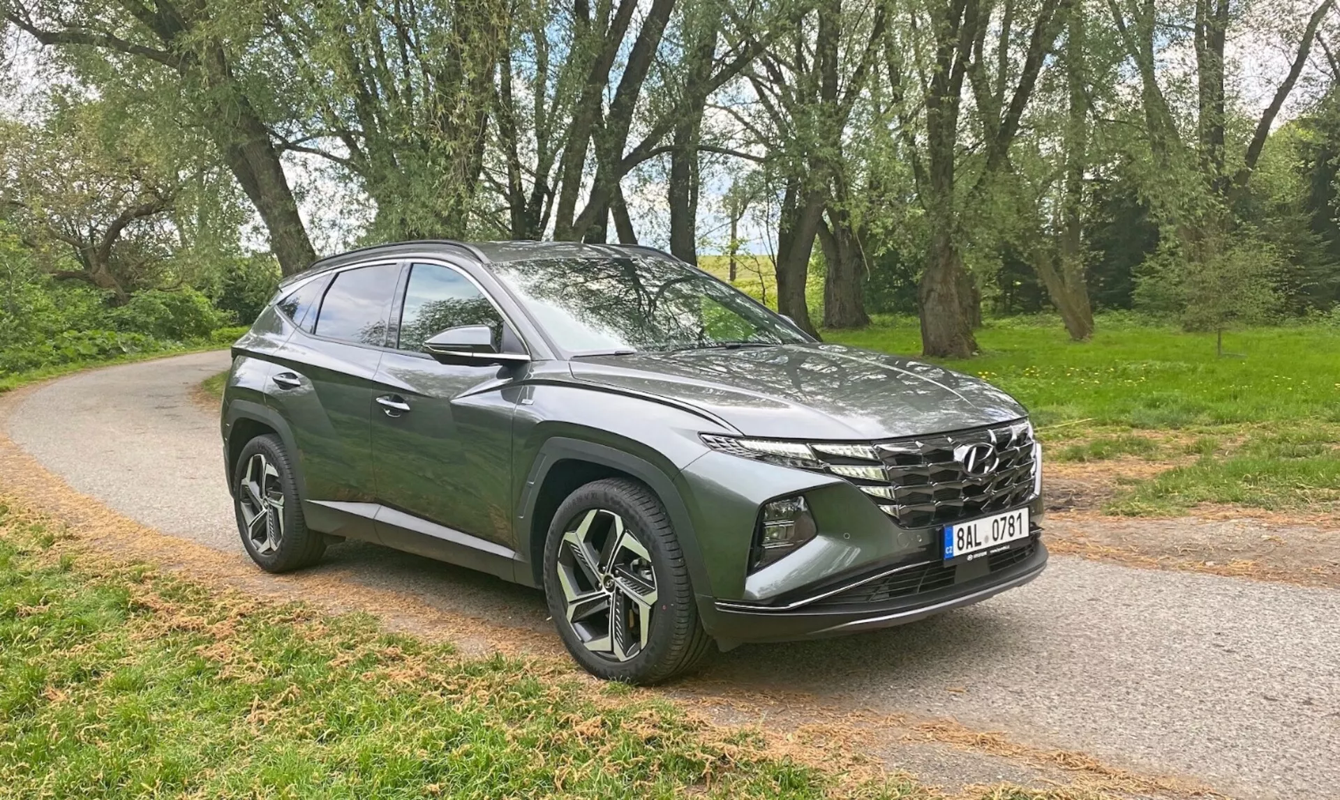 Hyundai Tucson 1.6 T-GDI Pure z 2020 roku w nieskazitelnej bieli, prezentujący swój elegancki design i nowoczesne funkcje na malowniczej drodze wśród wzgórz.