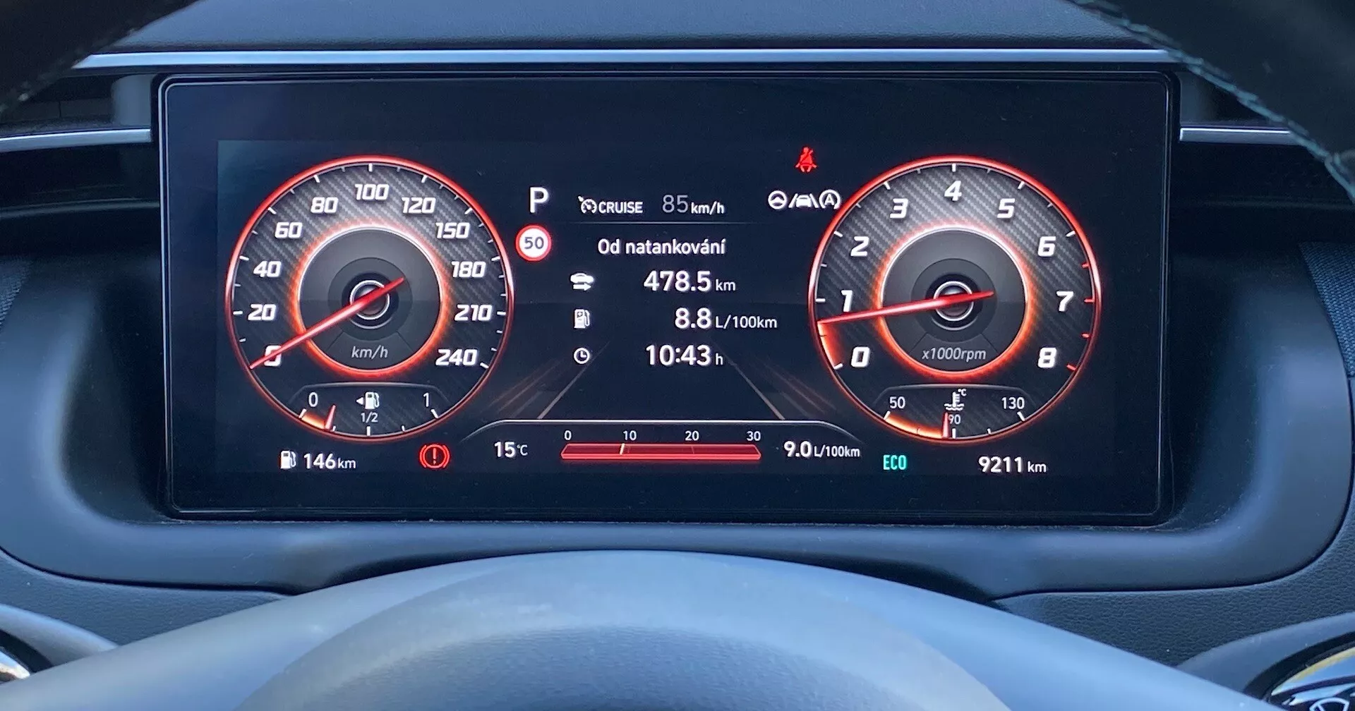 Zbliżenie cyfrowego panelu instrumentów w Hyundai Tucson 2020 z perspektywy kierowcy, pokazujące wyświetlacz wysokiej rozdzielczości prędkościomierza (do 260 km/h) i obrotomierza (do 7000 obr./min.), wskaźnik paliwa, informacje o podróży, ostrzeżenie o ciśnieniu w oponach, temperaturę zewnętrzną i różne ikony ostrzegawcze.