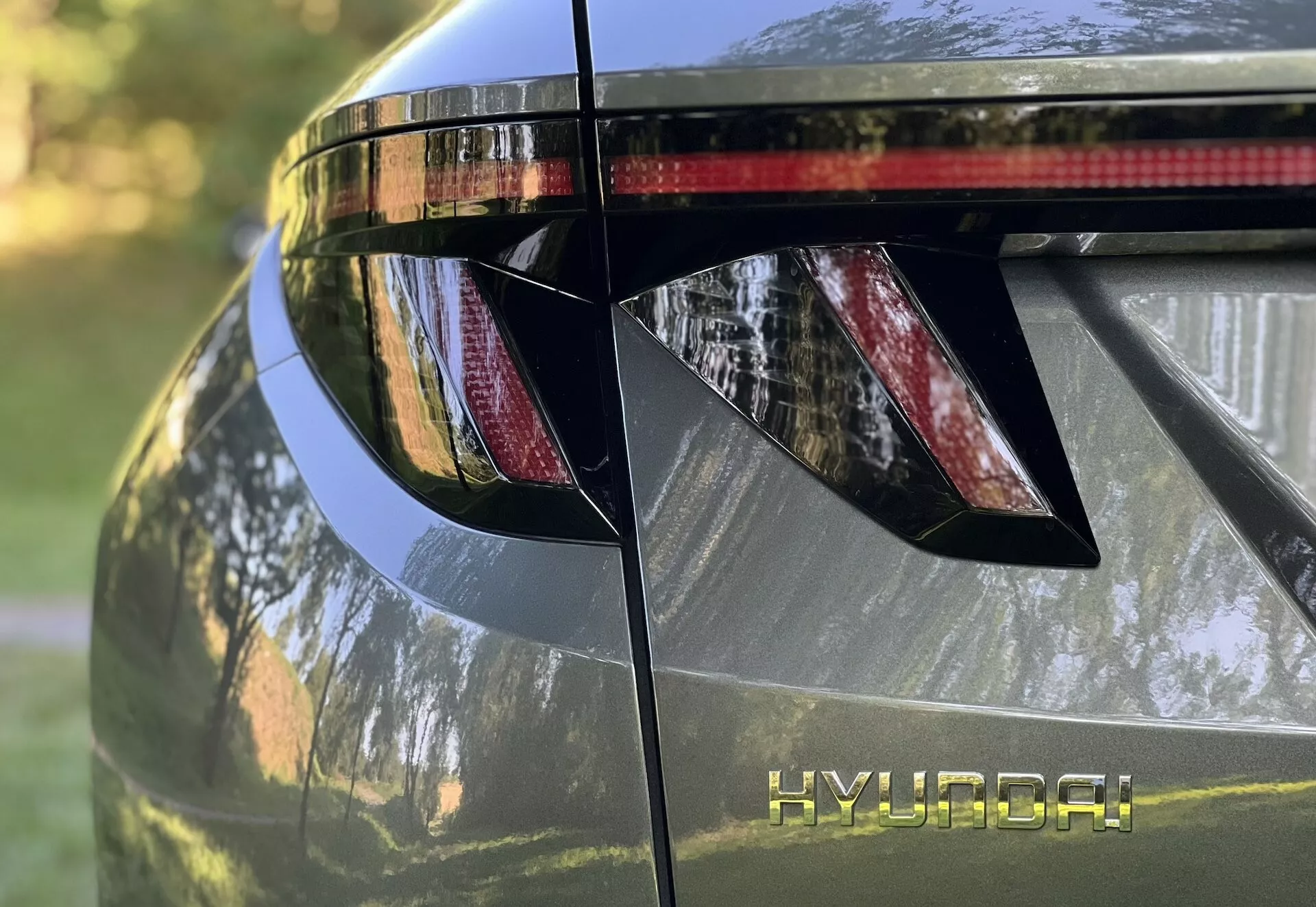 Zbliżenie na tylną sekcję Hyundai Tucson 2020, pokazujące kątowe światła tylne LED, branding HYUNDAI, zintegrowany tylny spoiler z światłem stopu, i lśniące metaliczne wykończenie