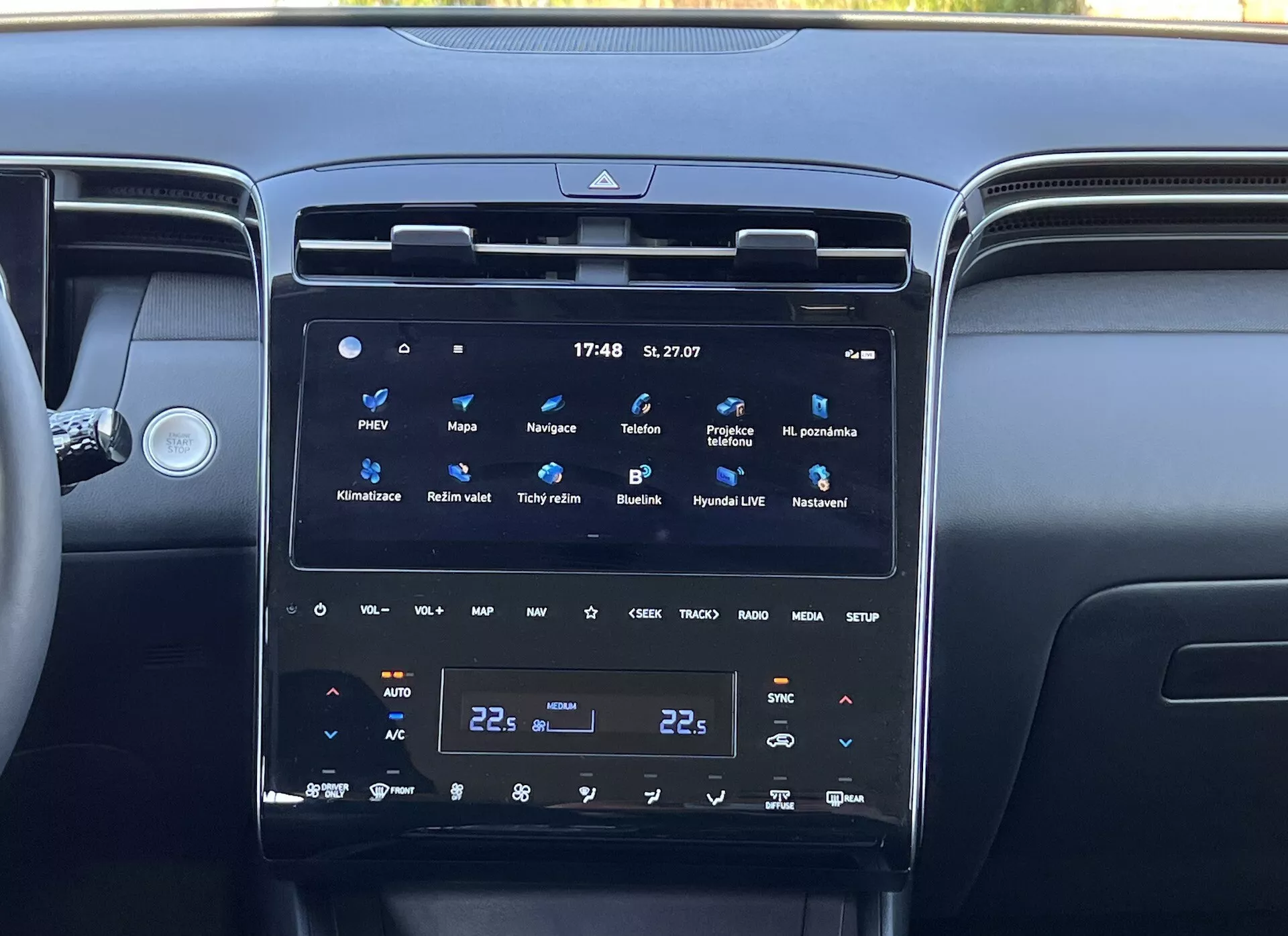 Wnętrze Hyundai Tucson 2020 przedstawiające konsolę środkową z dużym, pionowym dotykowym ekranem systemu infotainment, dwustrefową klimatyzację i otaczające nawiewy powietrza, odzwierciedlające nowoczesną technologię pojazdu i luksus