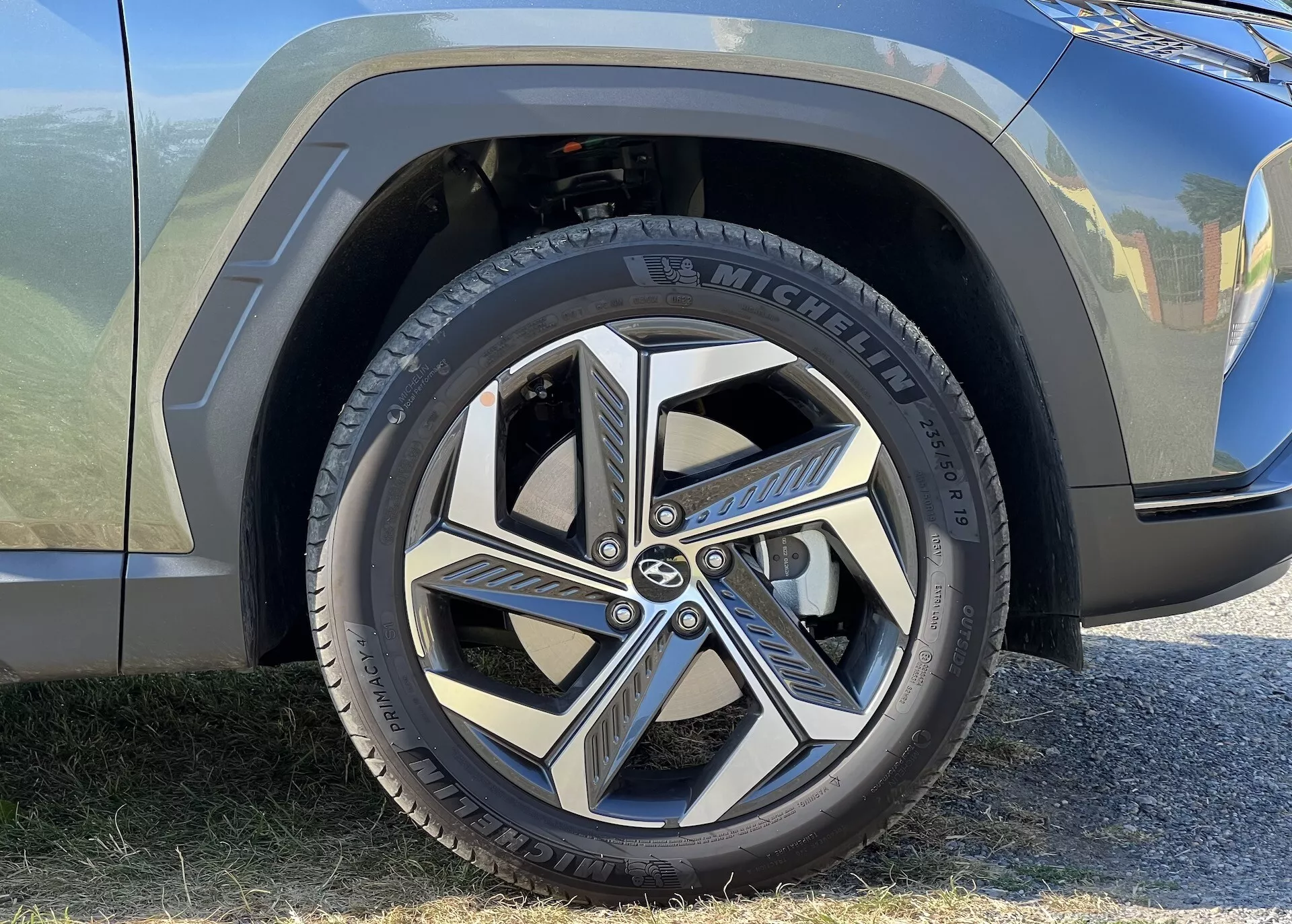 Zbliżony widok na przednie koło i część błotnika Hyundai Tucson 2020, przedstawiający oponę Michelin i dynamiczny, wieloramienne wzornictwo felgi aluminiowej, podkreślające nowoczesną estetykę motoryzacyjną i branding