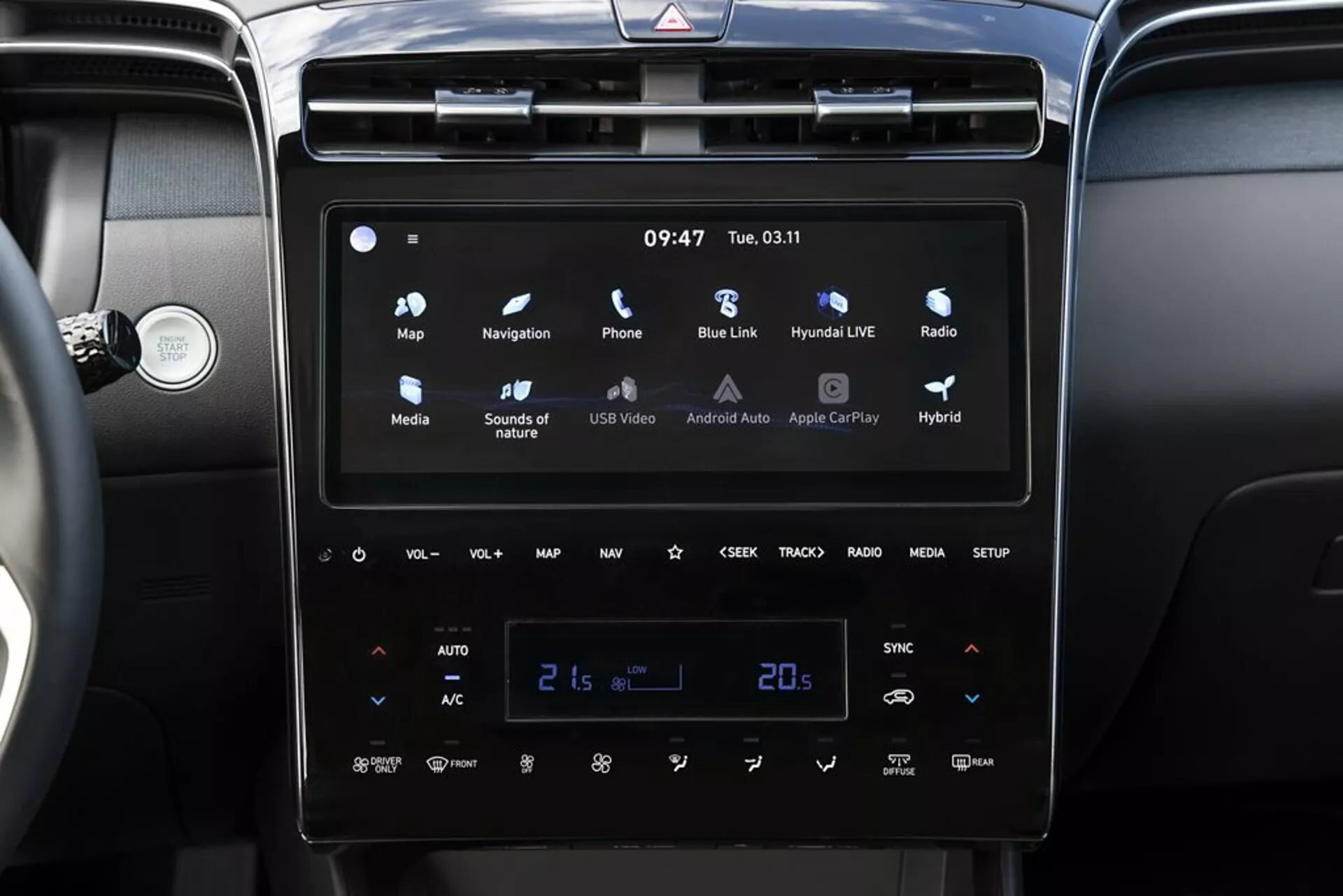 Wnętrze Hyundai Tucson 2020 z nowoczesnym systemem infotainment z ekranem dotykowym, Android Auto i Apple CarPlay, automatyczną klimatyzacją dwustrefową ustawioną na 21 stopni Celsjusza i wskaźnikami pojazdu hybrydowego