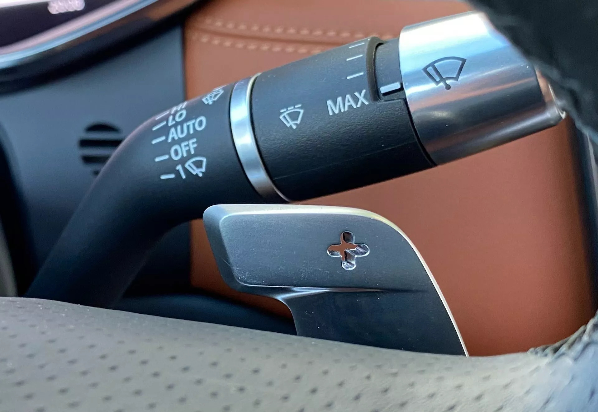 Zbliżenie kolumny kierownicy Jaguara XF 2021 prezentujące manetki sterujące; obejmuje manetkę kierunkowskazów i sterowania reflektorami z automatycznymi reflektorami, kontrolą świateł przeciwmgielnych oraz łopatkę zmiany biegów do ręcznego wyboru przełożeń.
