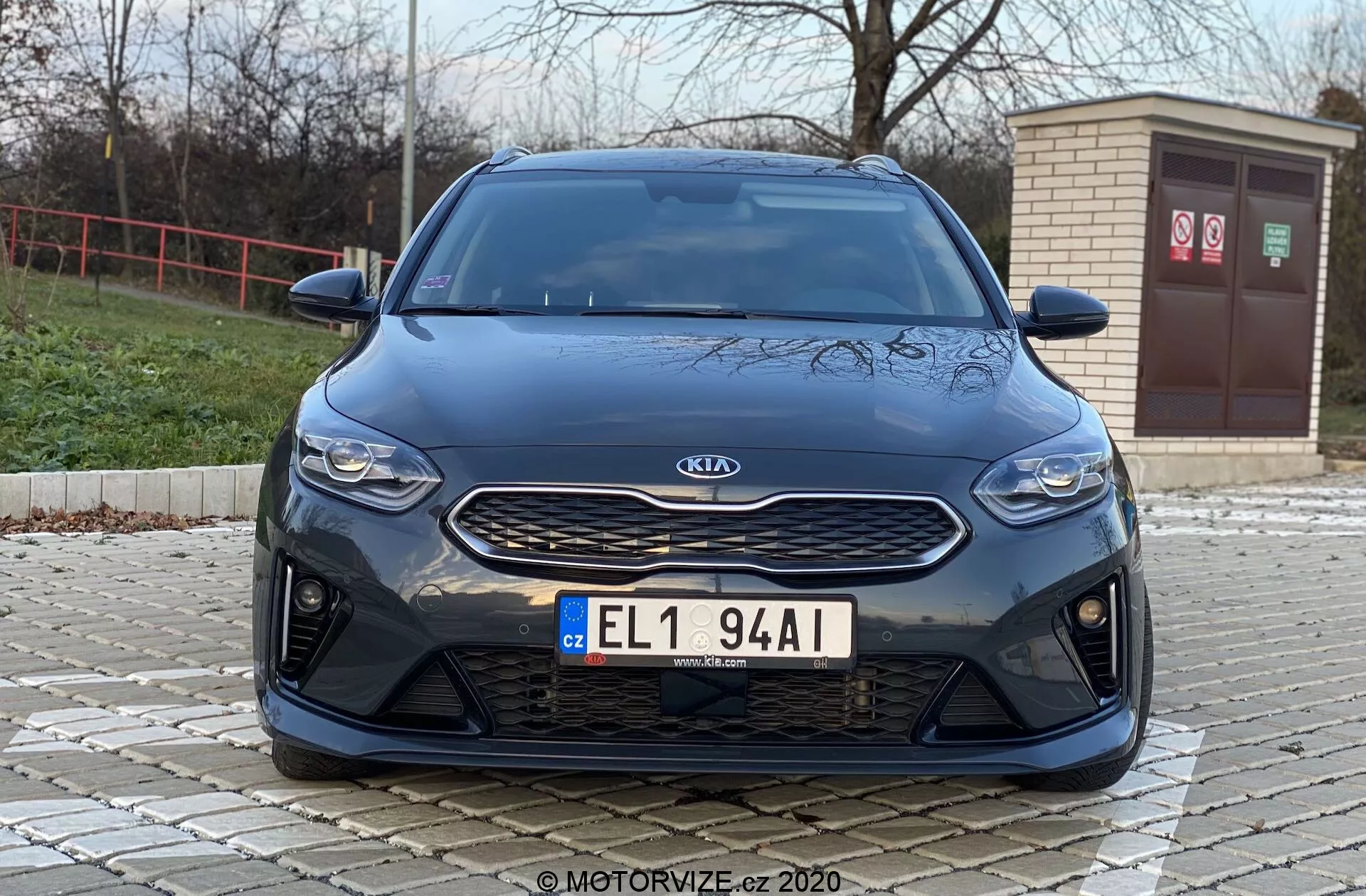 Widok z przodu samochodu Kia Ceed 2018 pod niskim kątem, ukazujący przednie elementy, takie jak kratka wlotu powietrza, reflektory i zderzak, z nowoczesną estetyką. Na zdjęciu wyróżnia się srebrny znaczek Kia na teksturowanej czarnej kratce, eleganckie poziome reflektory i przedni zderzak z dużymi wlotami powietrza, sugerującymi sportowe cechy wydajnościowe lub zaawansowane chłodzenie przepływu powietrza.