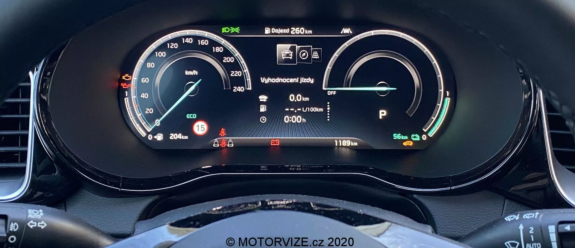 Zbliżenie na cyfrowy zestaw przyrządów Kia Ceed 2018 z perspektywy siedzenia kierowcy. Wyświetlacz zawiera prędkościomierz ze wskaźnikiem analogowym i cyfrowym odczytem, pokazującym 15 km/h. Po prawej stronie znajduje się wskaźnik mocy/baterii wskazujący pełne naładowanie akumulatora z zasięgiem 481 km. Inne elementy to wyświetlacz gotowości, informacje dla kierowcy ze wskaźnikami ostrzegawczymi, odczyt temperatury zewnętrznej 20,5°C oraz pojazd w trybie Park. Widoczny jest też górny łuk kierownicy o sportowym, płaskim dole.
