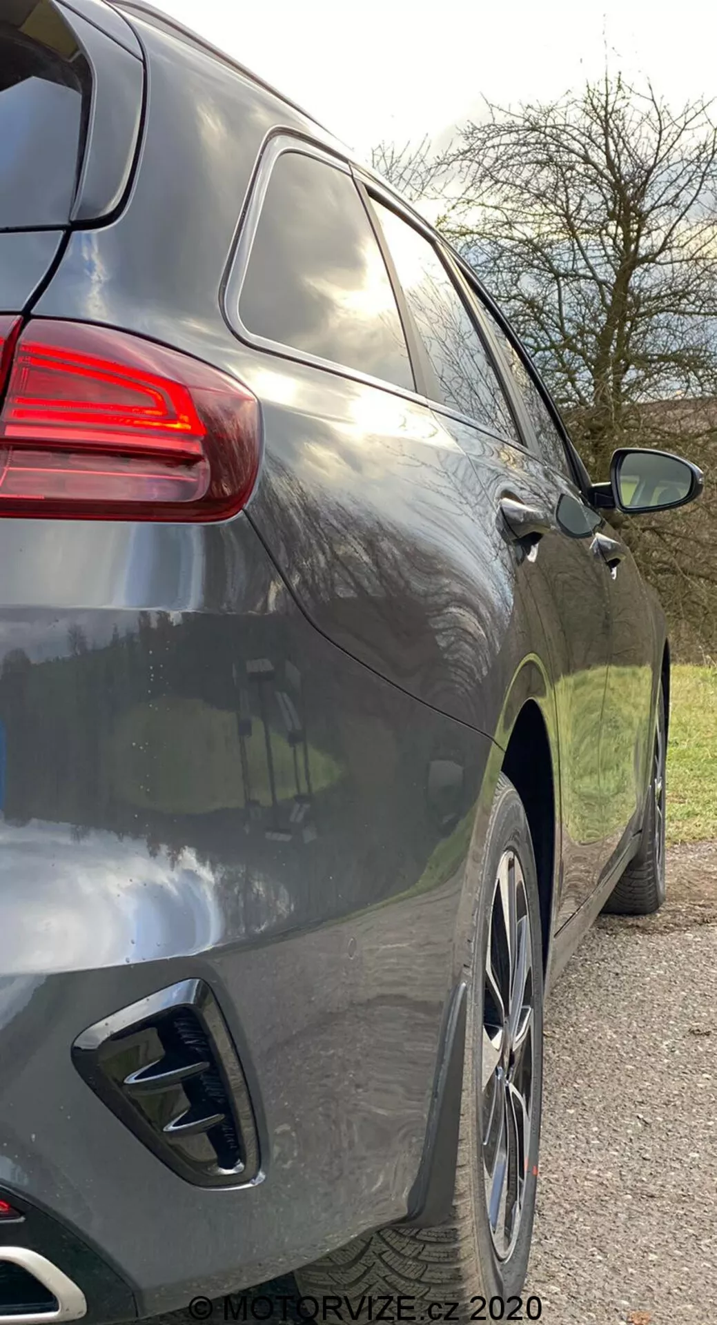 Zbliżenie widoku bocznego prawego nowoczesnego SUV-a pod lekko tylnym kątem, ukazujące tylną część i boczny profil od klamki tylnych drzwi do tylnych świateł, cechującego się gładkimi aerodynamicznymi liniami, ciemnym metalicznym lakierem, dużymi felgami aluminiowymi, podwójnymi końcówkami wydechu, przyciemnianymi szybami i tylnym światłem o nowoczesnym wyglądzie.