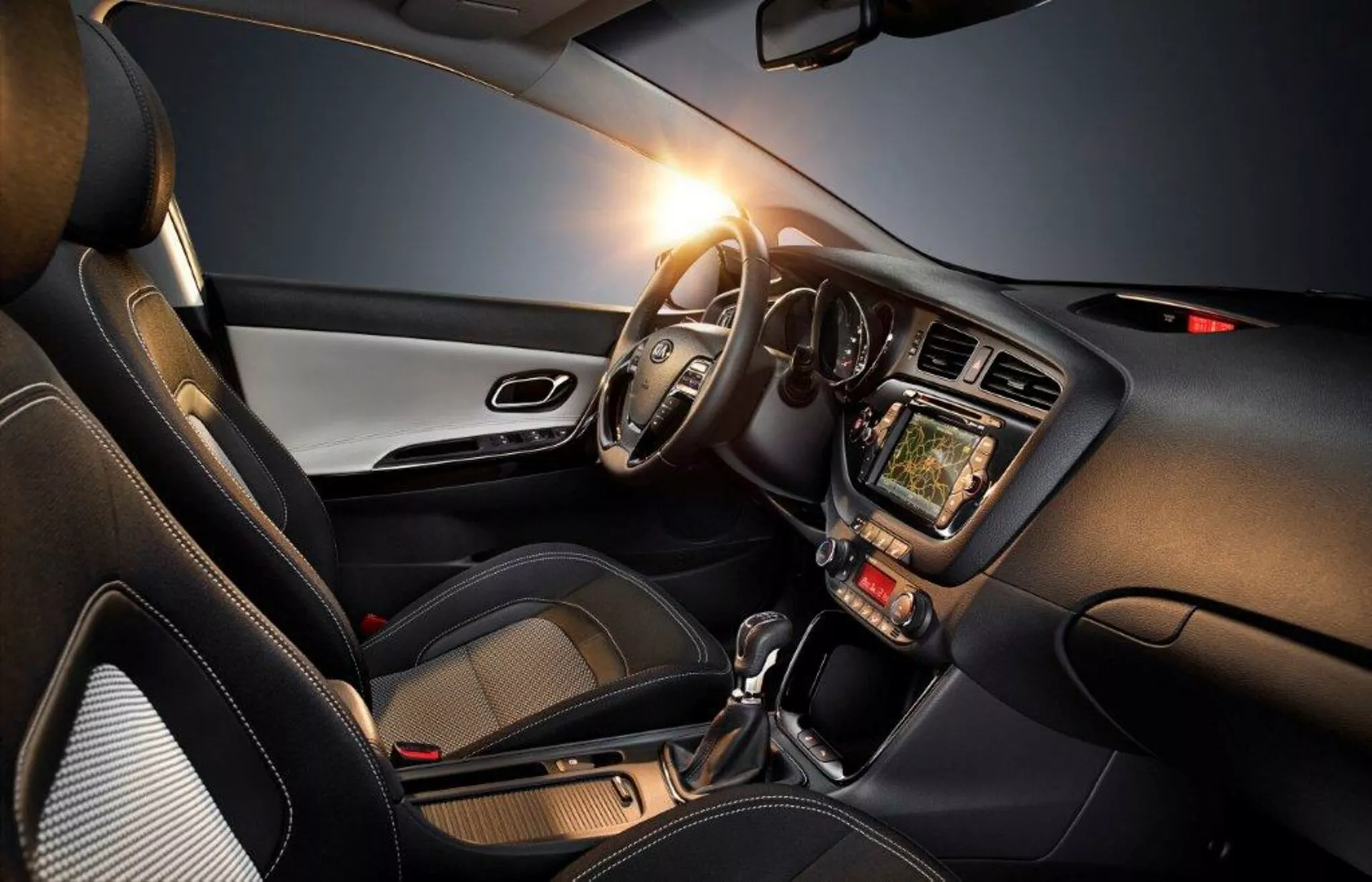 Wnętrze Kia Cee'd 2009 podkreślające stronę kierowcy z kierownicą po lewej stronie, zegary, system infotainment z ekranem dotykowym, kontroli klimatyzacji, automatyczną skrzynią biegów i nowoczesnymi akcentami designu, podkreślającymi technologię, komfort i sportowy aspekt