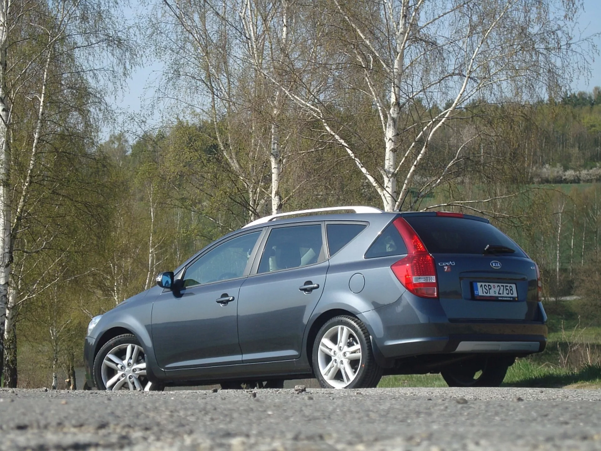 Szare kombi Kia Ceed z 2009 roku, prezentujące boczną i tylną cześć nadwozia, z akcentem na aerodynamiczną linię dachu, tylne światła i tylną szybę, zaparkowane na zewnątrz