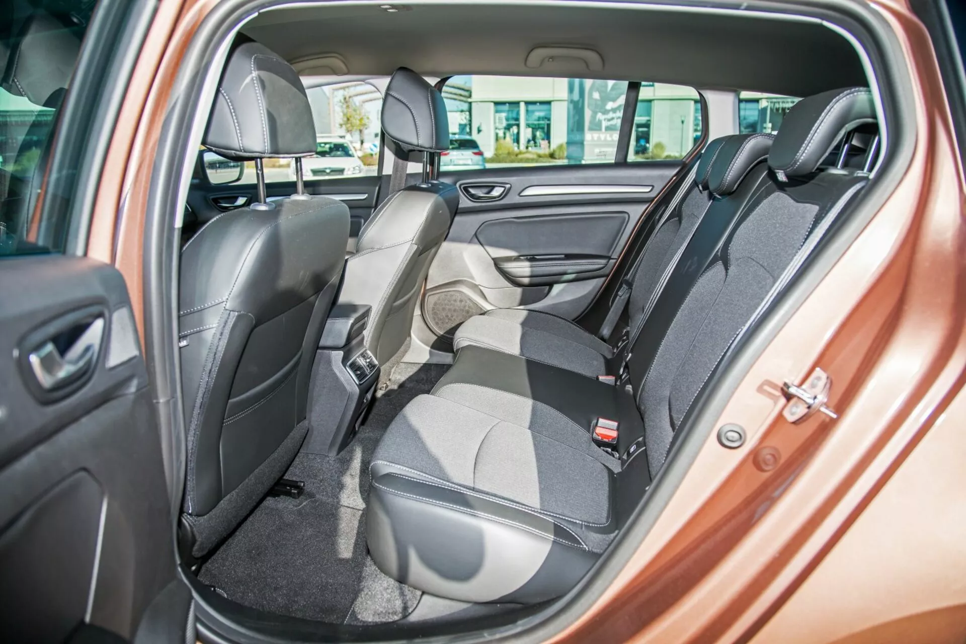 Wnętrze Kia Ceed 2009 z dwukolorową tylną ławką z jednym siedzeniem złożonym do przodu na bagaż, pasy bezpieczeństwa, zagłówki, sterowanie elektrycznymi szybami i głośnik na drzwiach, podkreślające elastyczne układanie siedzeń i luksusowy design