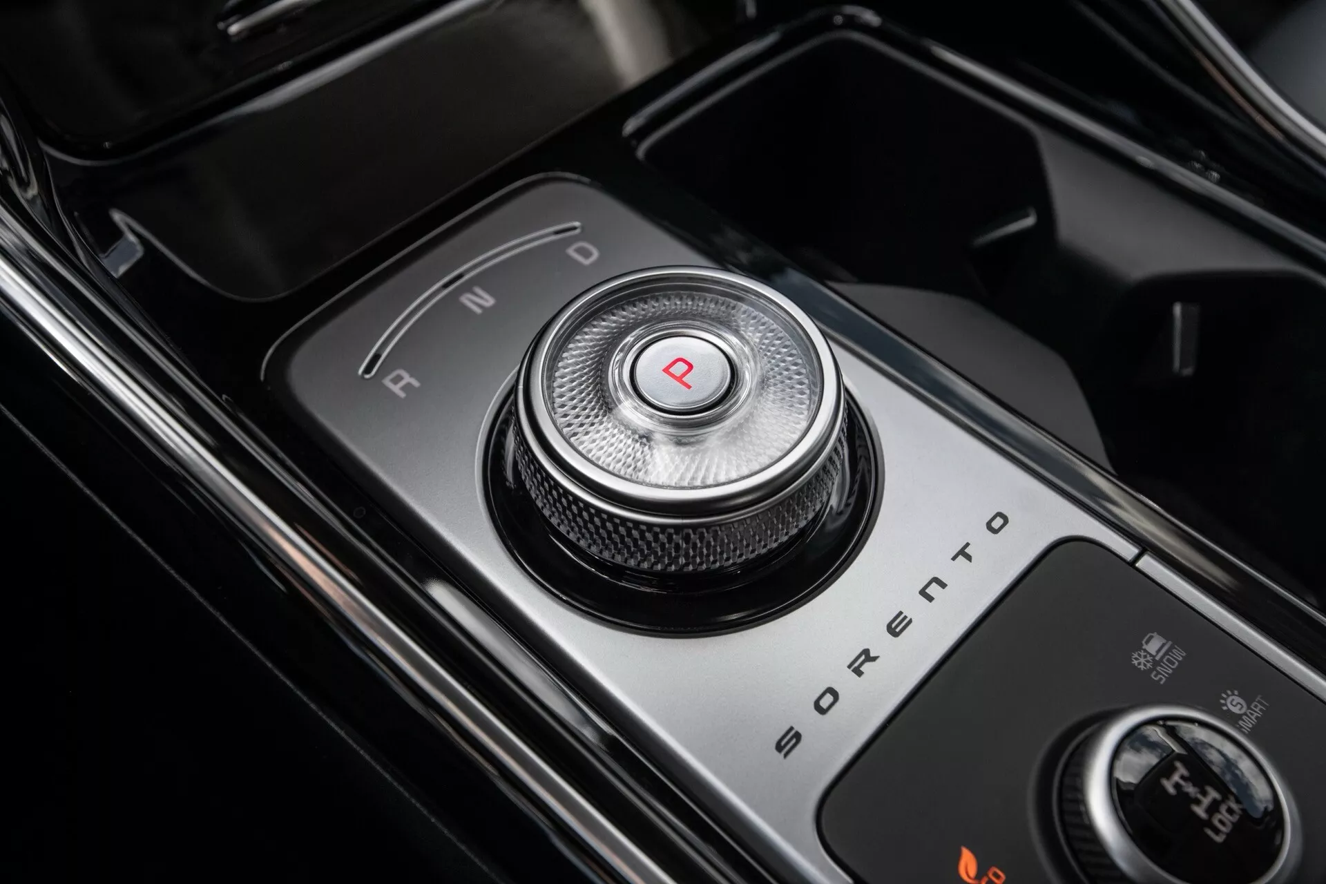 Zbliżenie na obrotowy selektor biegów Kia Sorento MQ4 facelift 2024 w pozycji 'P', podkreślające nowoczesne i luksusowe wnętrze z połyskującymi czarnymi powierzchniami i metalicznymi akcentami