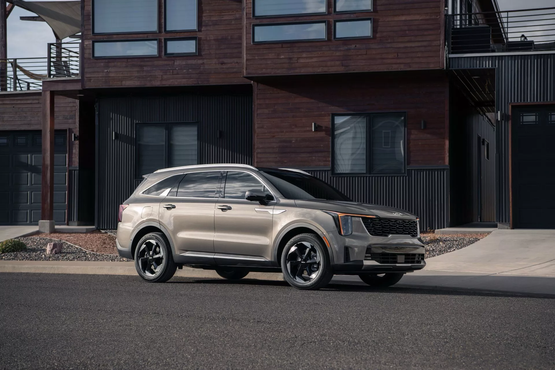 Model Kia Sorento MQ4 lifting 2024 zaparkowany na miejskiej ulicy, prezentowany z perspektywy trzech czwartych z przodu, co podkreśla jego nowoczesny design z wyrazistą przednią kratą, reflektorami LED, alufelgami wieloszprychowymi oraz stylowym dwukolorowym schematem lakierowania na tle współczesnych rezydencji.