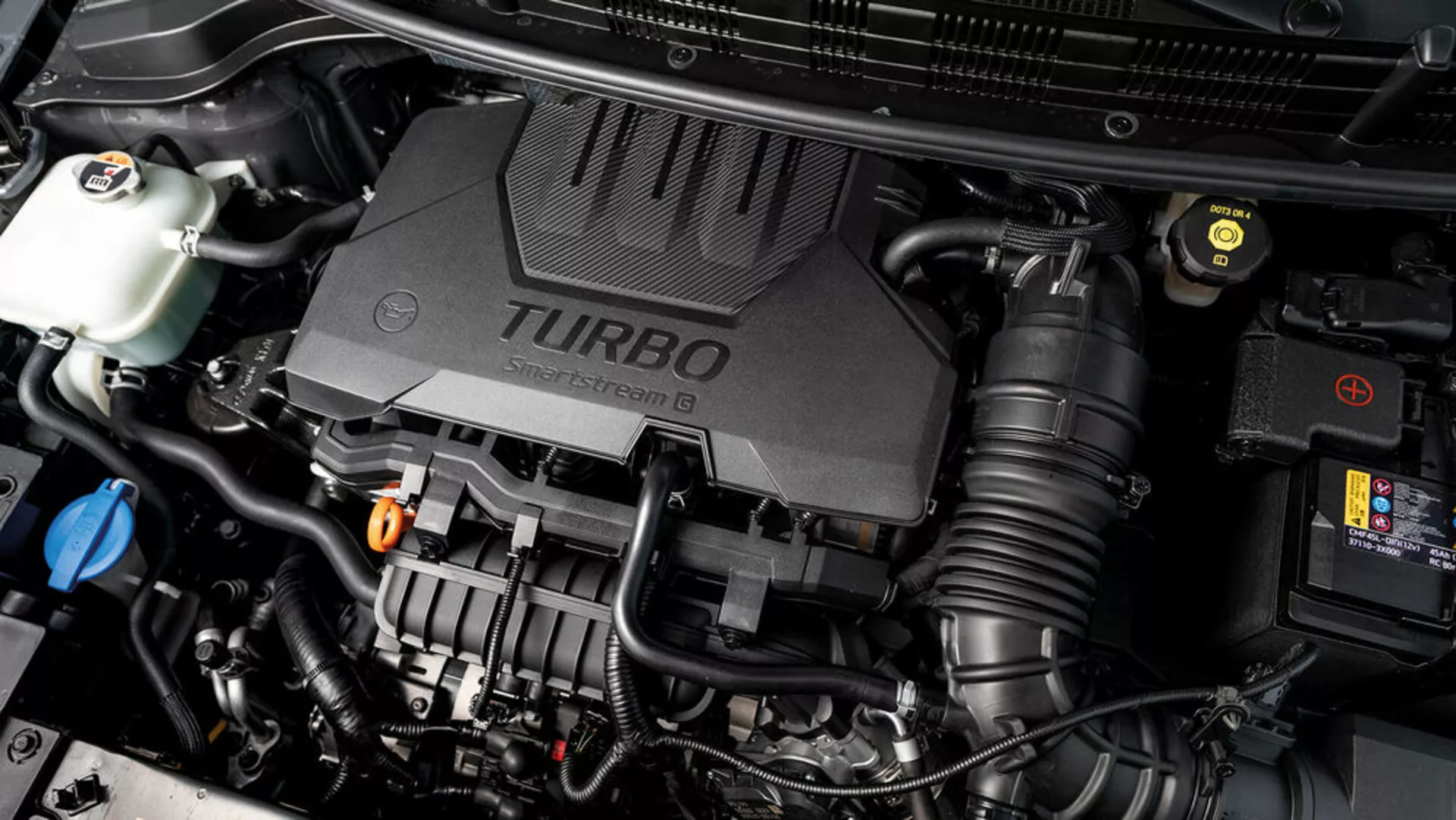 Zbliżenie na komorę silnika Kia Stonic 2017 z pokrywą silnika turbo i widocznymi różnymi komponentami mechanicznymi, prezentujące technologiczne aspekty pojazdu