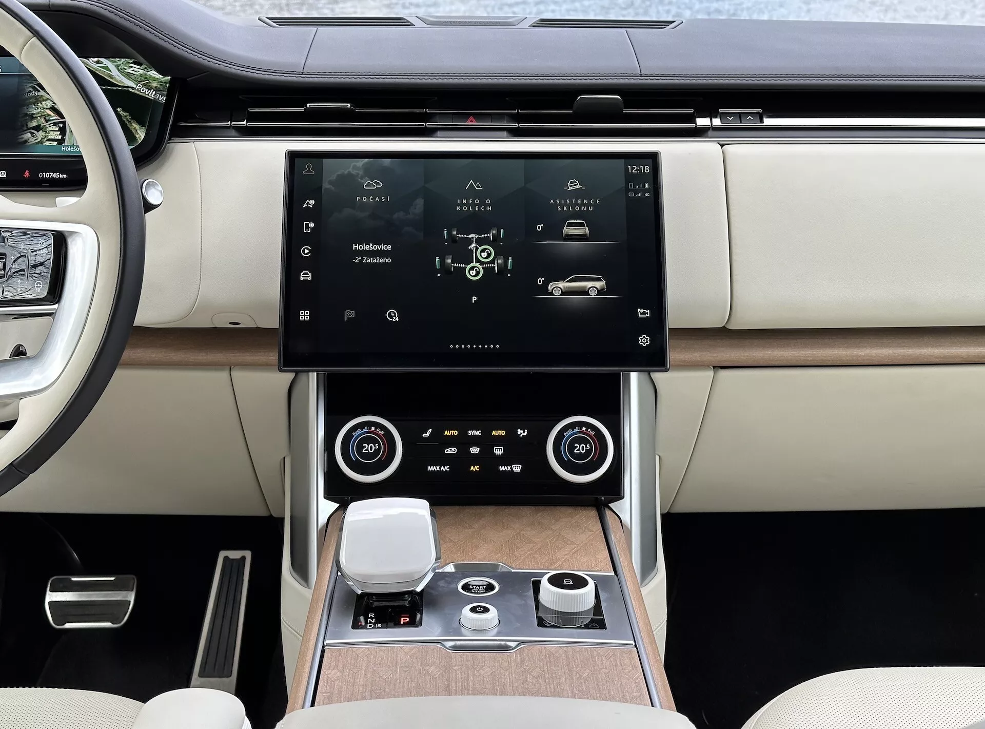 Land Rover Range Rover 2021 z nowoczesnym wnętrzem, skupiający się na konsoli środkowej i systemie infotainment z wysokorozdzielczym dotykowym ekranem, wentylacją z akcentami chromu, dwustrefową kontrolą klimatu, obrotowym pokrętłem do nawigacji systemu i luksusowymi siedzeniami z dwukolorowej skóry z detalami wykończenia drewnem.