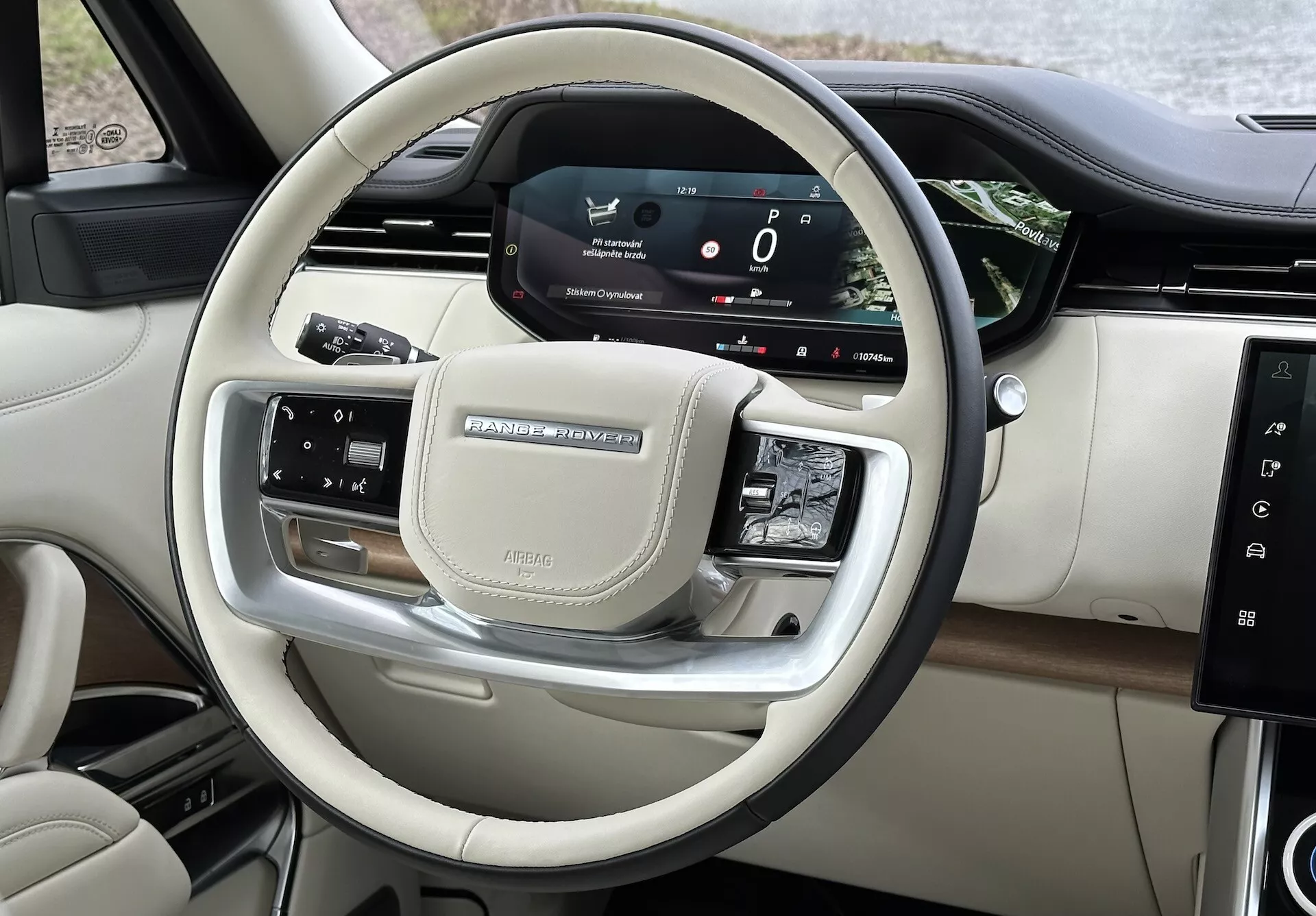 Widok wnętrza Land Rover Range Rover 2021, przedstawiający sterowanie z kierownicy oraz cyfrowy kokpit kierowcy z chromowanymi elementami i luksusowymi wykończeniami
