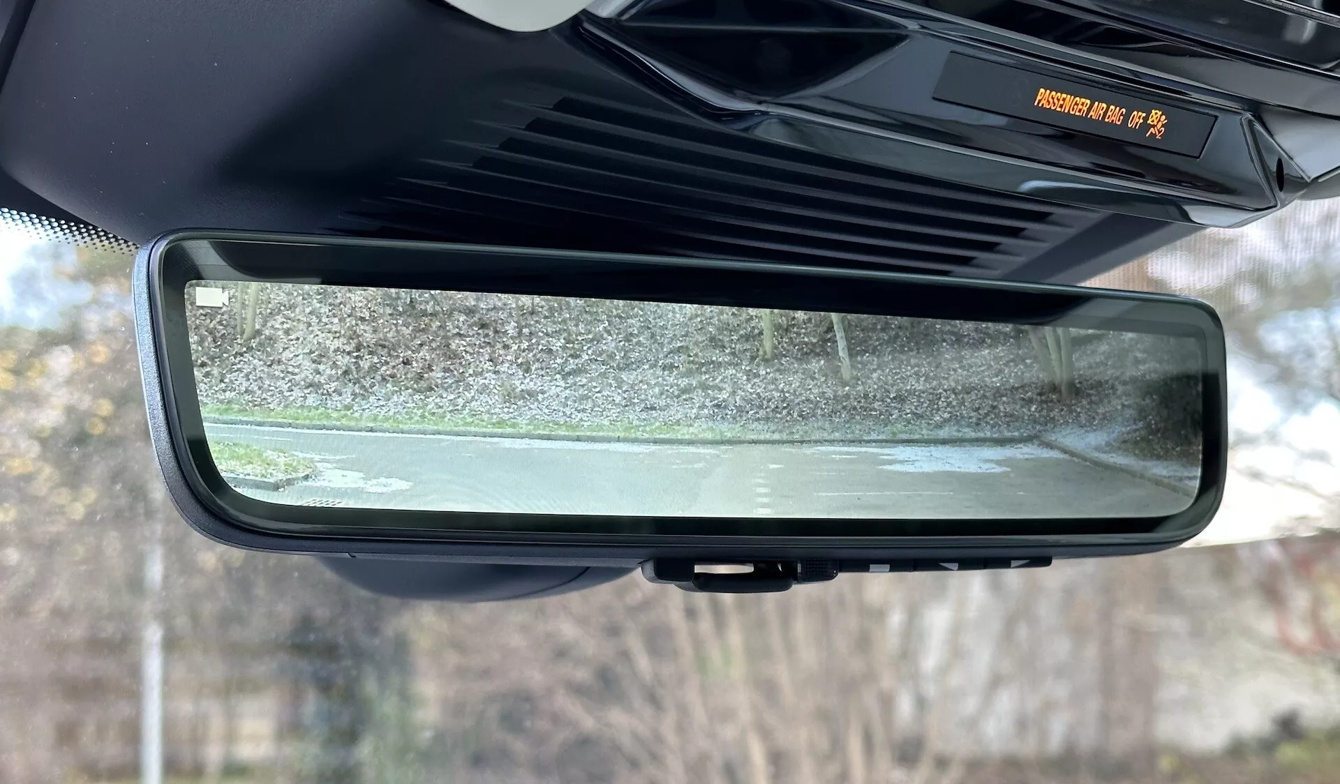 Zbliżenie na elektrochromowe lusterko wsteczne samościemniające się w Range Rover 2021, podkreślając jego bezramowy design, cechy kabiny wewnętrznej i odbitą scenę zewnętrznych okolic w bezruchu