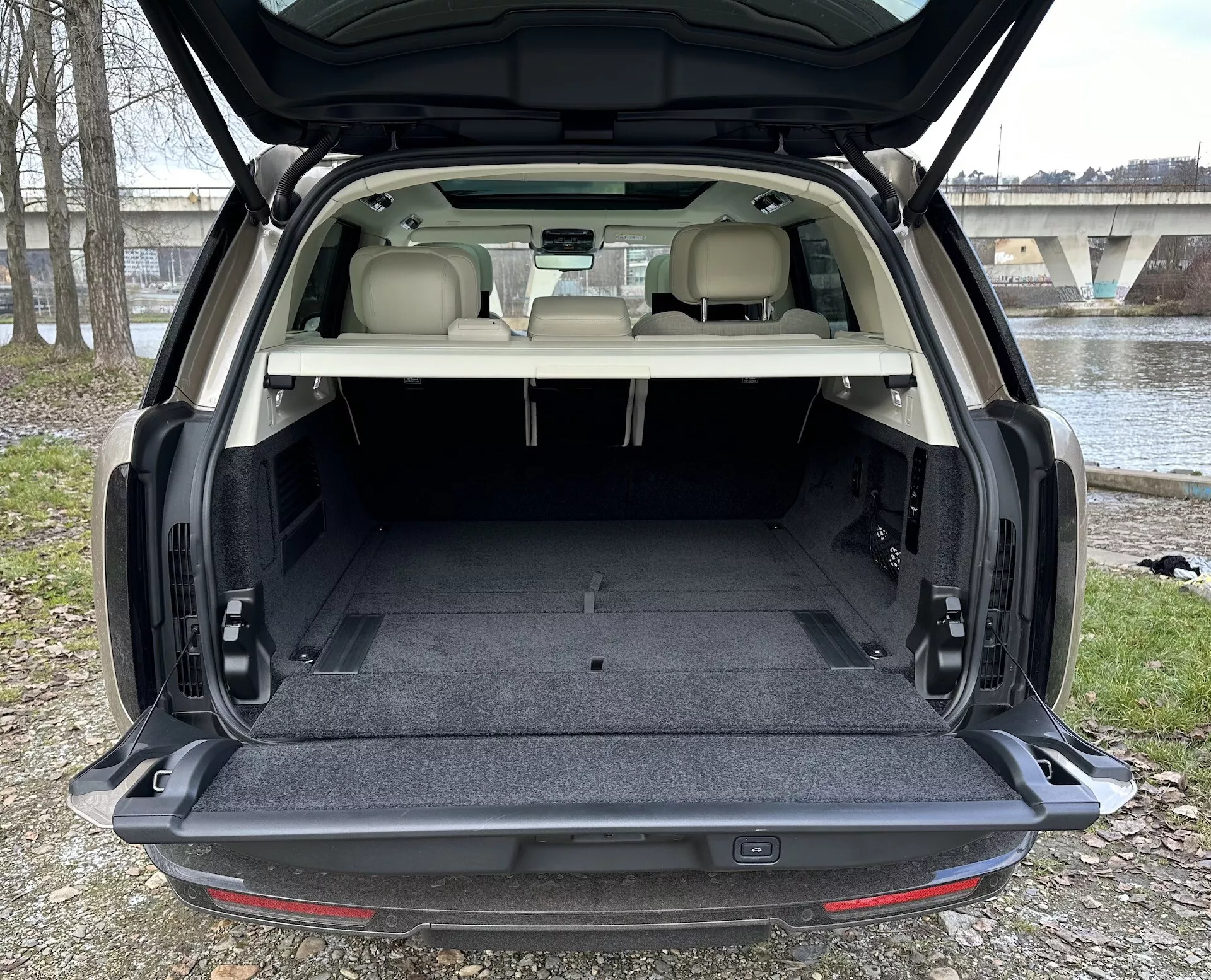 SUV Land Rover Range Rover 2021 pokazujący przestronny tylny bagażnik z otwartą klapą, tapicerkę w jasnym kolorze kontrastującą z ciemnym dywanikiem, oraz elementy wyposażenia wnętrza w tym oświetlenie przestrzeni bagażowej i możliwe mechanizmy składania siedzeń