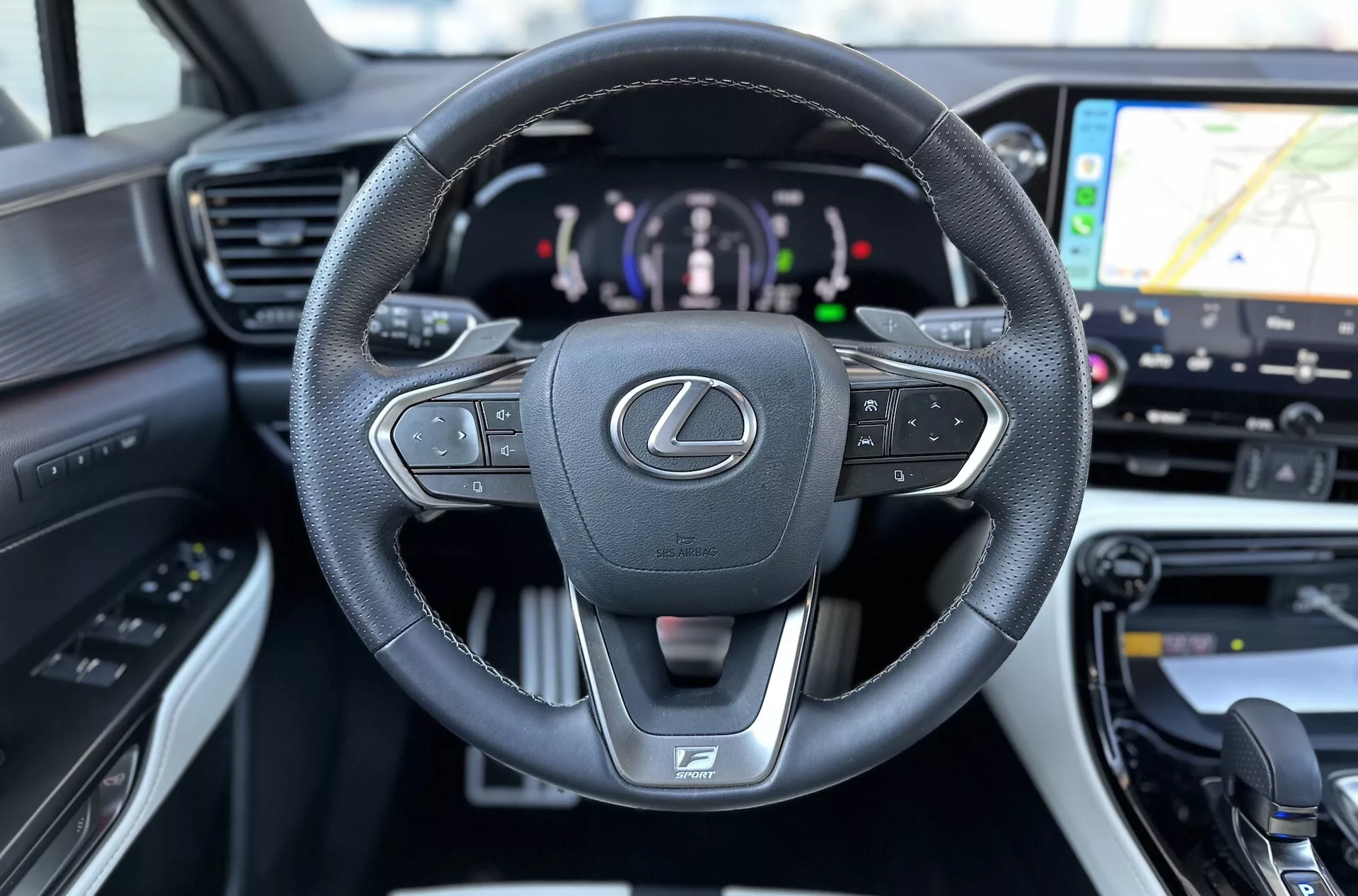 Wnętrze Lexusa NX 2021 skupia się na wielofunkcyjnej kierownicy obszytej skórą z emblematem Lexusa i logo F SPORT, cyfrowym zestawie wskaźników wskazującym napęd hybrydowy i wglądzie w system nawigacji GPS na systemie rozrywki