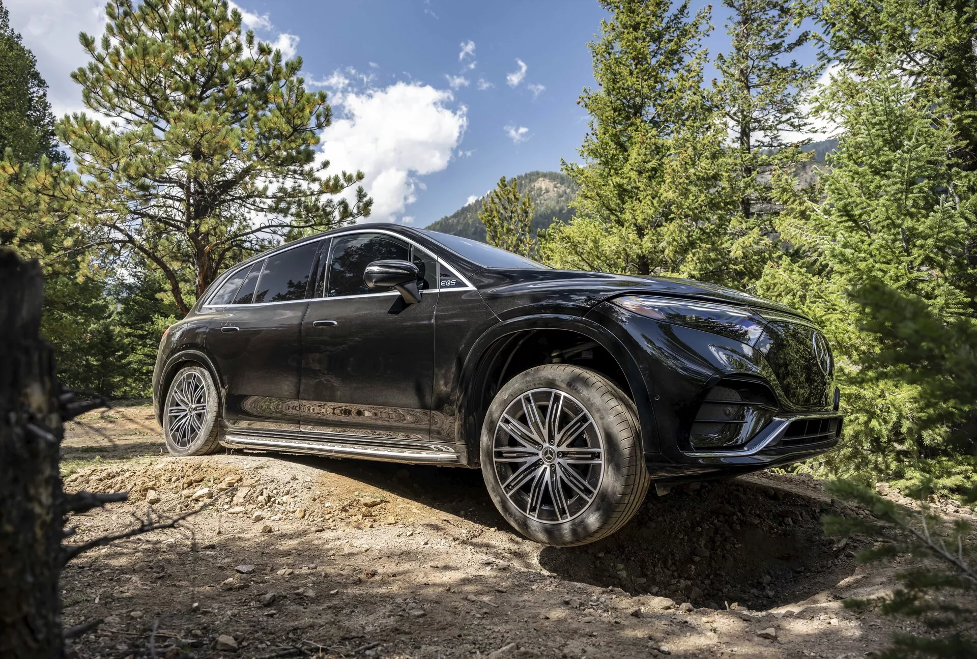 Widok z trzech czwartych z przodu na Mercedesa EQS SUV z 2022 roku, ukazujący jego elegancki design, zaawansowane reflektory LED, panoramiczny dach i wysokiej klasy felgi aluminiowe w wyrafinowanym miejskim otoczeniu.