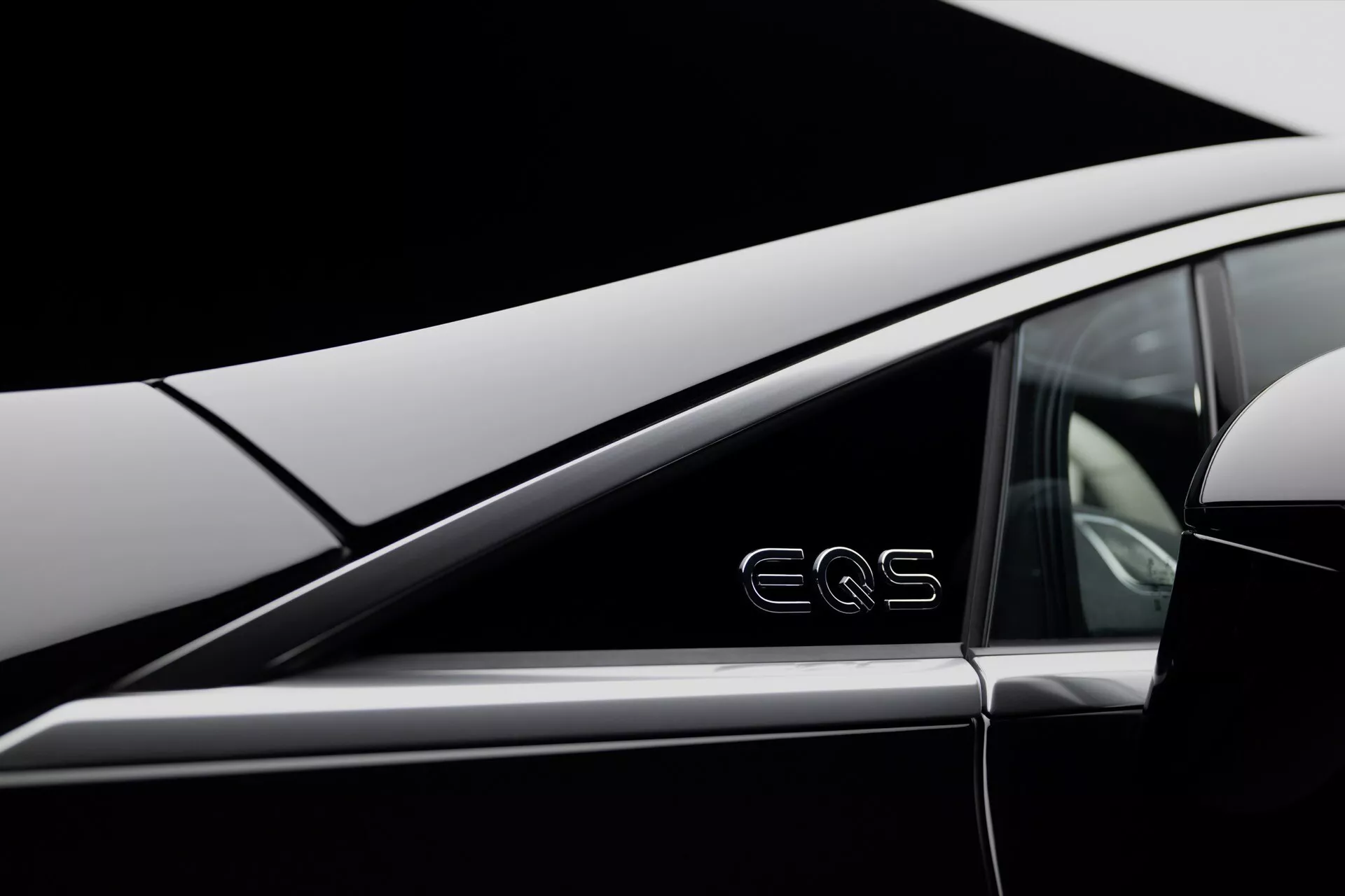 Zbliżenie na Mercedes-Benz EQS 2024 prezentujący elegancki design tylnej szyby pasażerskiej i klamki drzwi wypukłej z emblematem 'EQS', podkreślający zaawansowaną technologię pojazdów elektrycznych i luksusowy design.