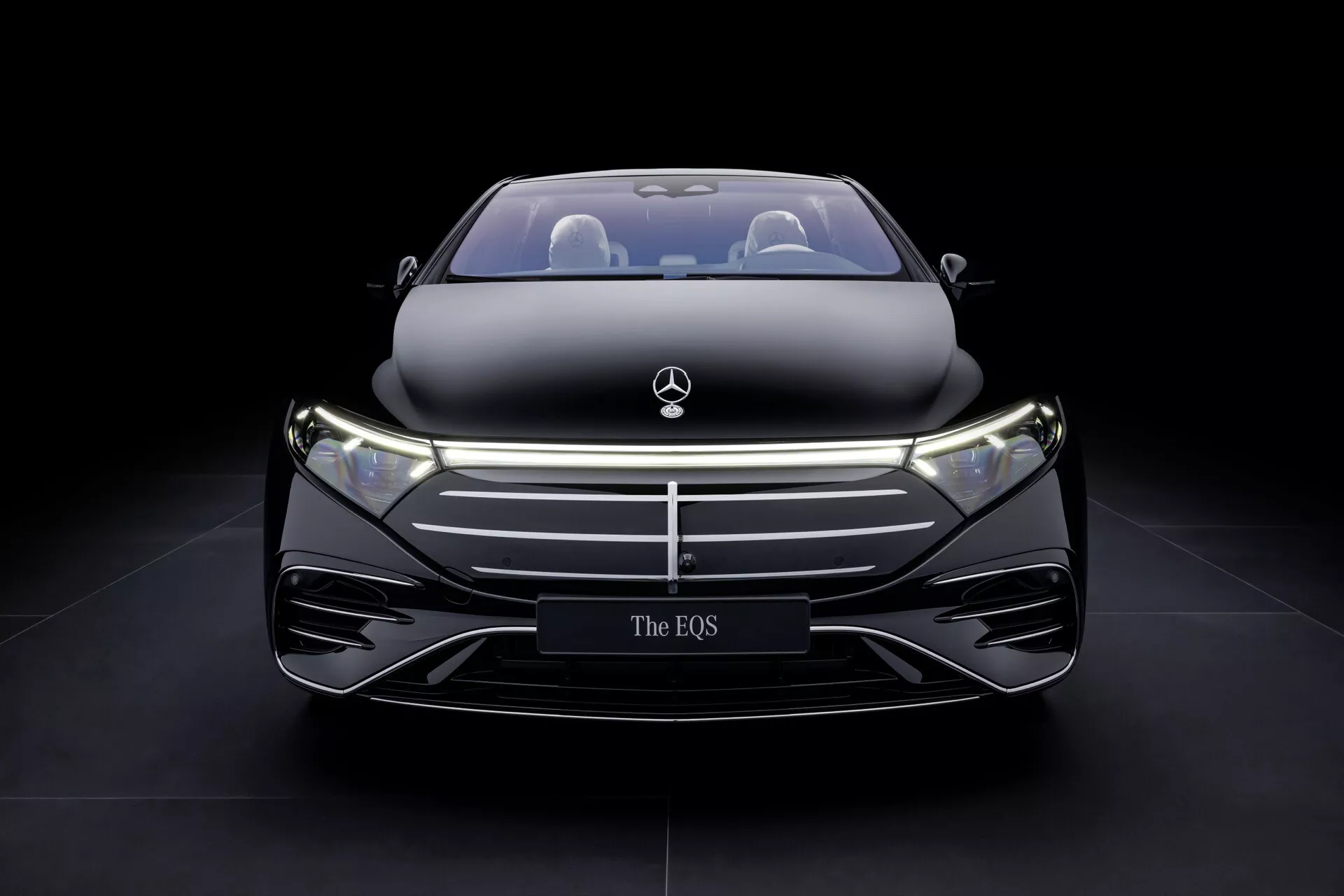 Model Mercedes-Benz EQS 297 facelift z 2024 roku prezentuje swój elegancki przedni design z zamkniętą kratką, LED-owymi reflektorami i wysokim połyskiem na ciemnym tle, podkreślając luksus i zaawansowaną technologię pojazdów elektrycznych